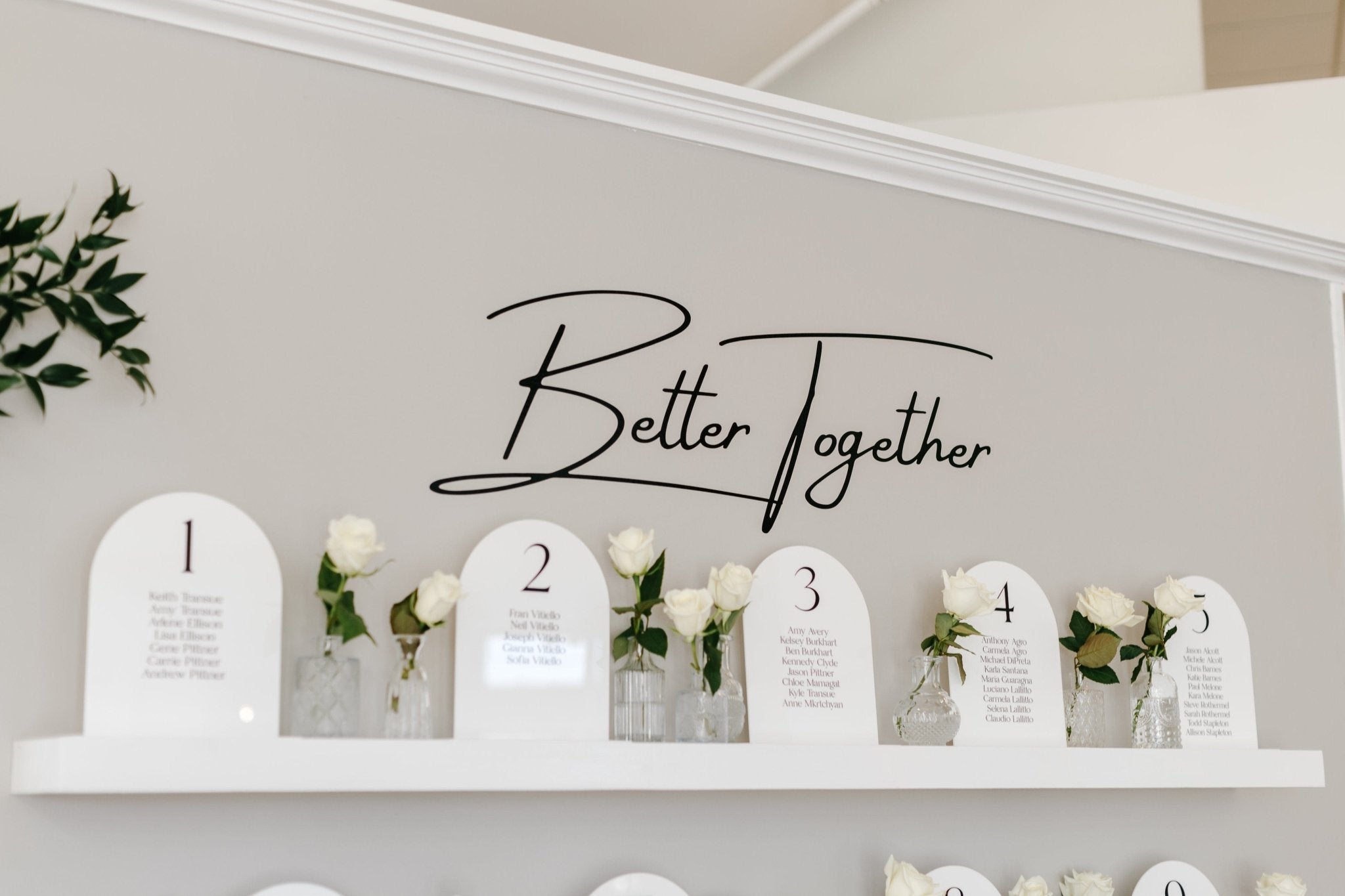 An elegant wedding seating chart and table number display featuring arched acrylic signs with personalized design, set up for a wedding reception.
