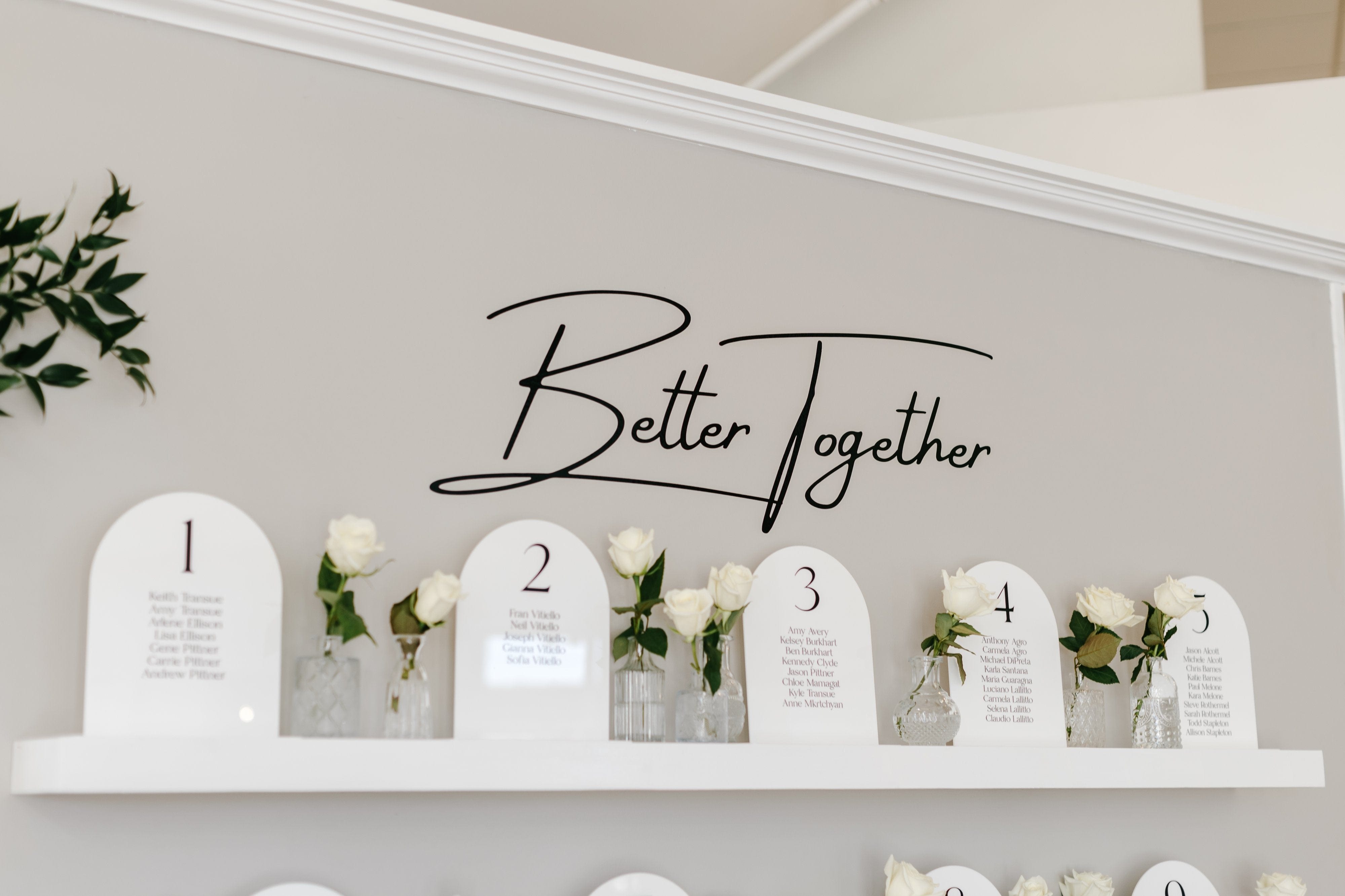An elegant wedding seating chart and table number display featuring arched acrylic signs with personalized design, set up for a wedding reception.