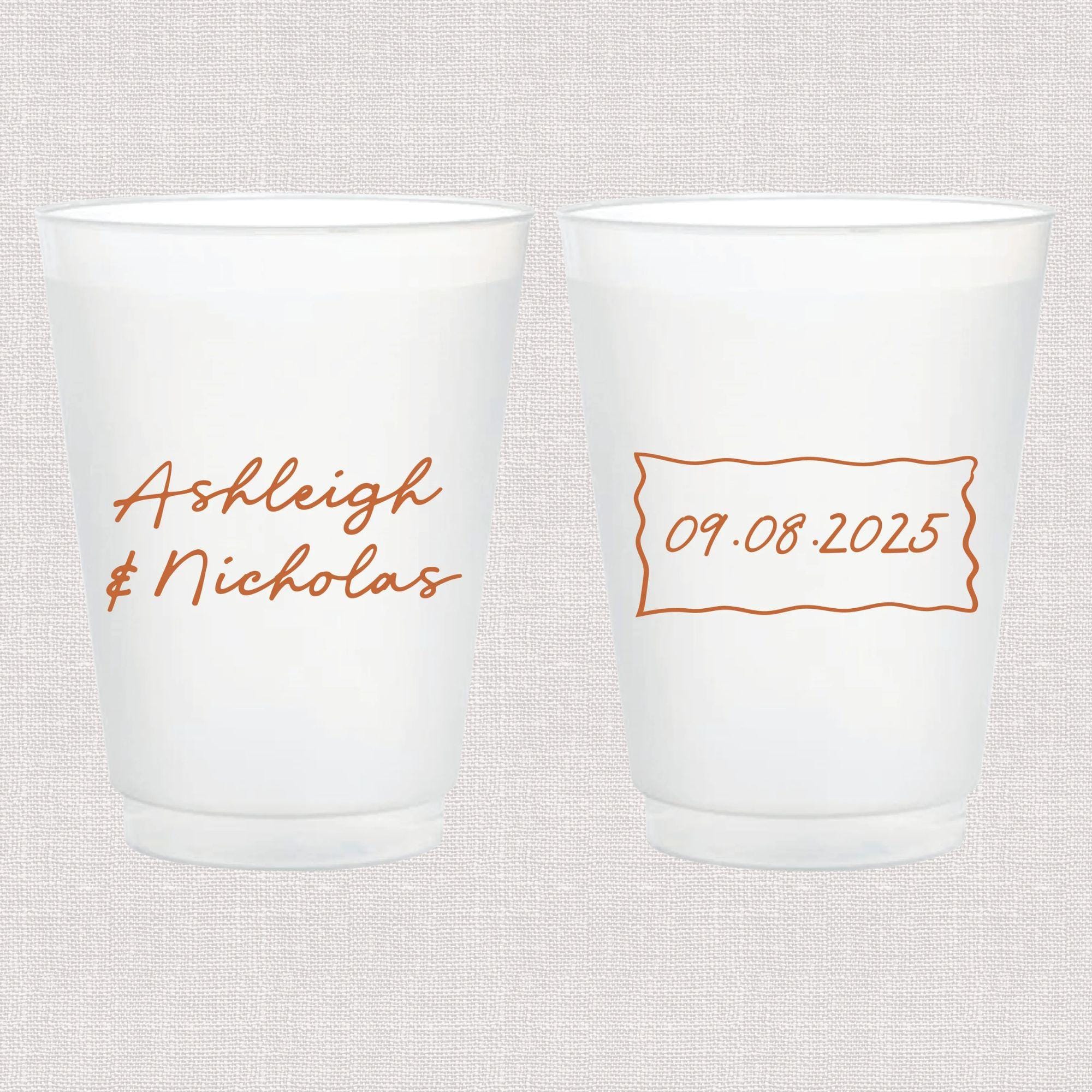 Pair of frosted white cups with copper script names and date, personalized for wedding favors.