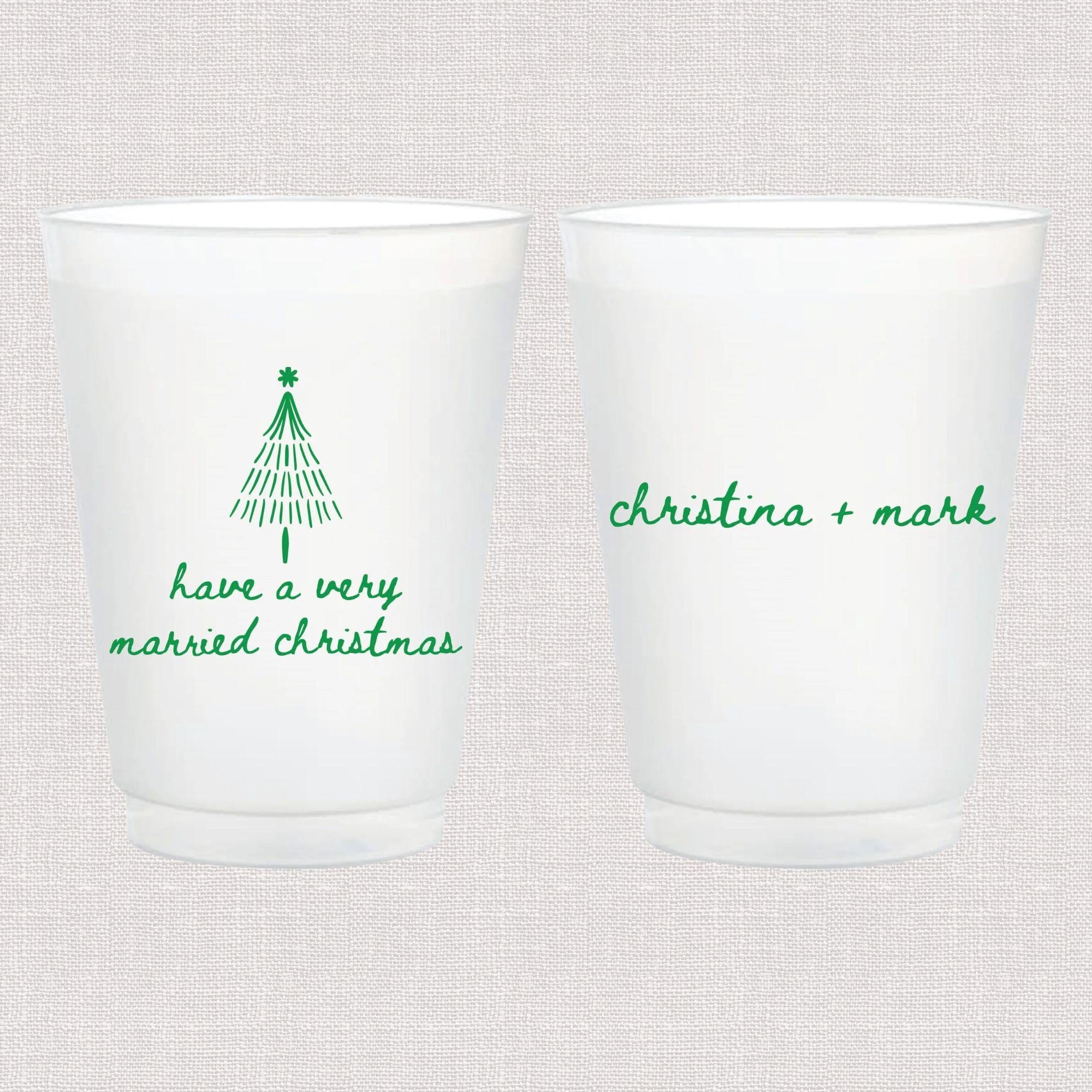 Two frosted plastic cups with green text, one featuring a Christmas tree and "have a very married christmas," the other personalized with "christina + mark"