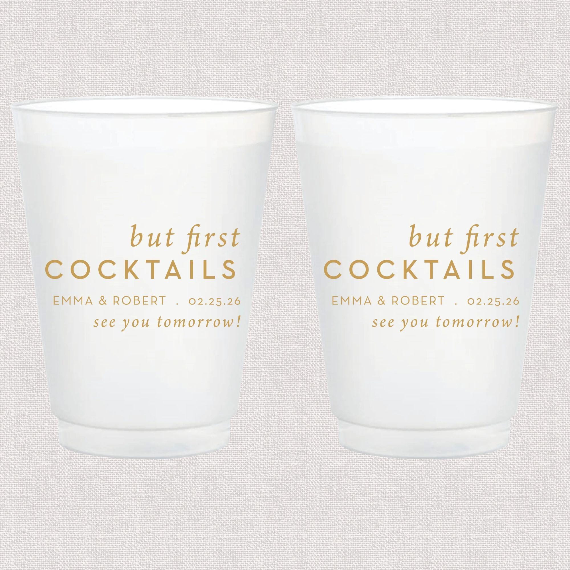Two frosted white cups with gold text reading "but first COCKTAILS" personalized with names and date, "see you tomorrow" below.