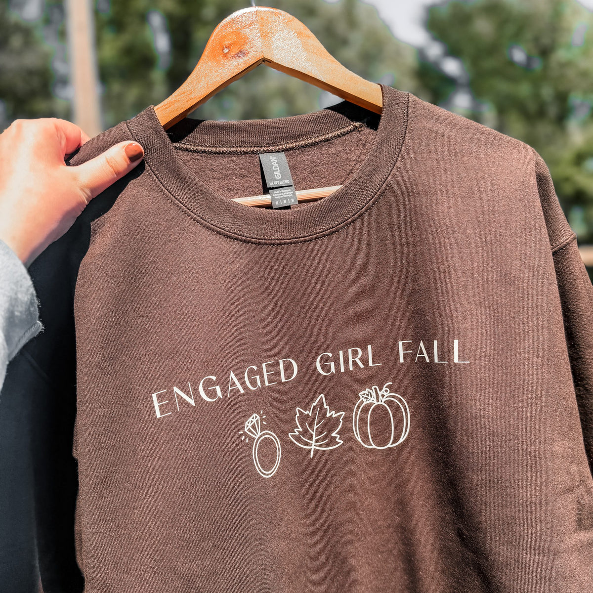 Close up of Engaged Girl Fall sweatshirt with diamond ring, leaf and pumpkin icons in ivory cream