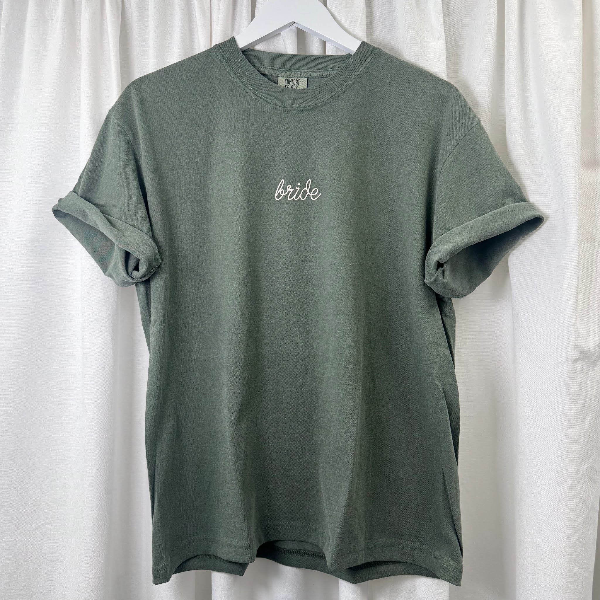 Flat lay of hunter green Comfort Colors 1717 embroidered Bride shirt, showing full garment and embroidery placement