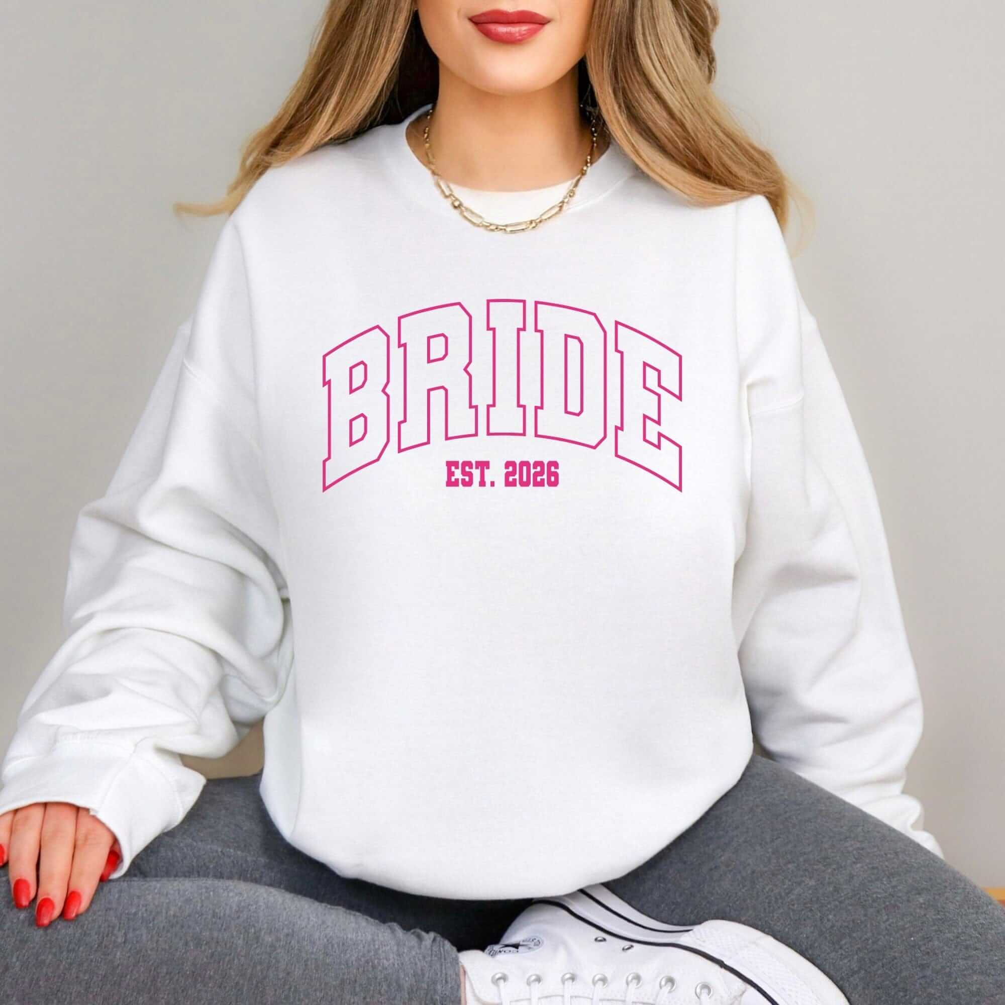 A white crewneck sweatshirt featuring a pink outline graphic design, suitable for a bridal event.