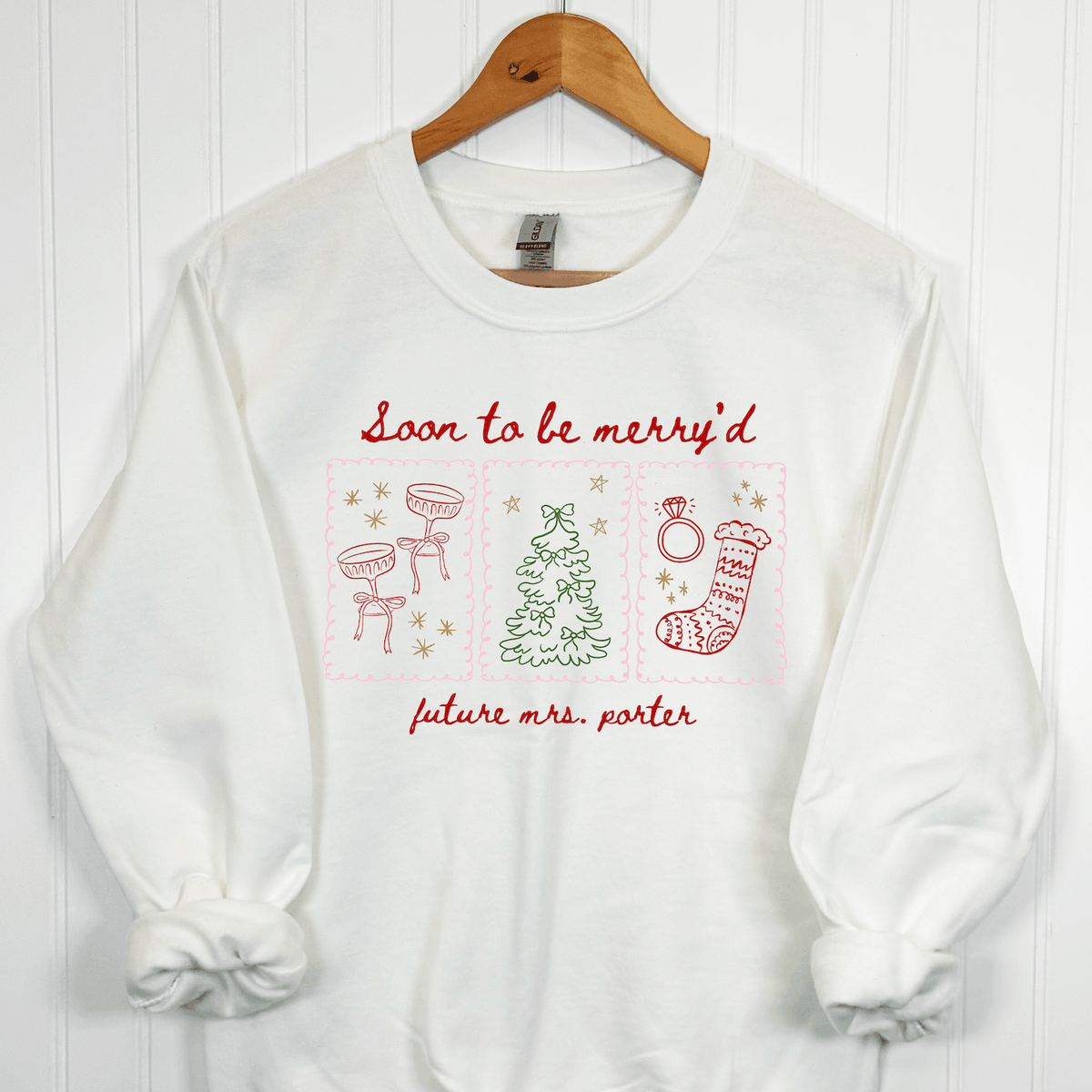 White Christmas bride crewneck sweatshirt with red Soon to Be Merry'd lettering, colorful holiday illustrations, and personalized Future Mrs. name.