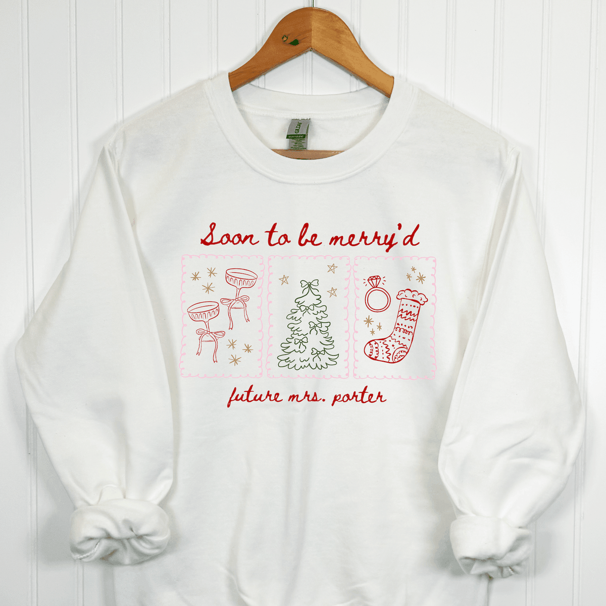 White Christmas bride crewneck sweatshirt with red Soon to Be Merry'd lettering, colorful holiday illustrations, and personalized Future Mrs. name.