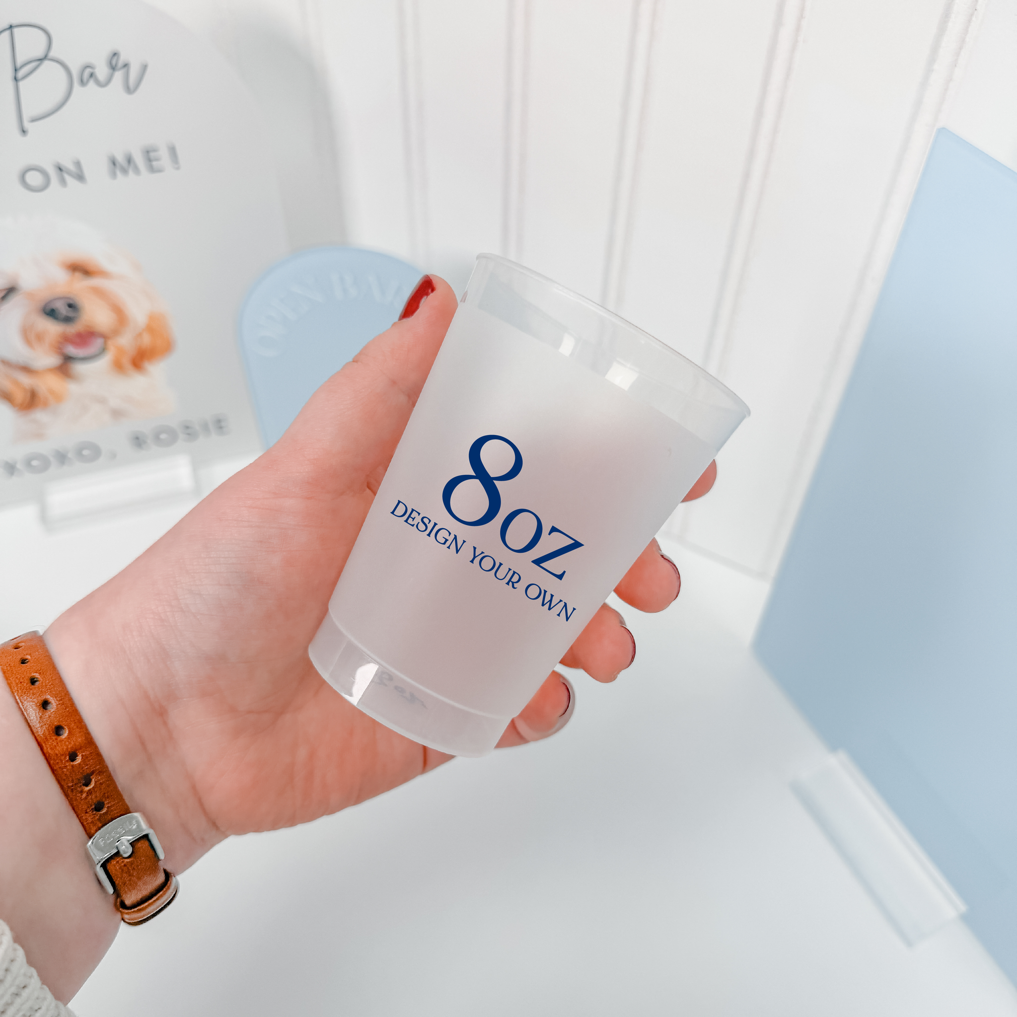 Hand holding an 8 oz frosted shatterproof cup with a custom navy design, shown for size