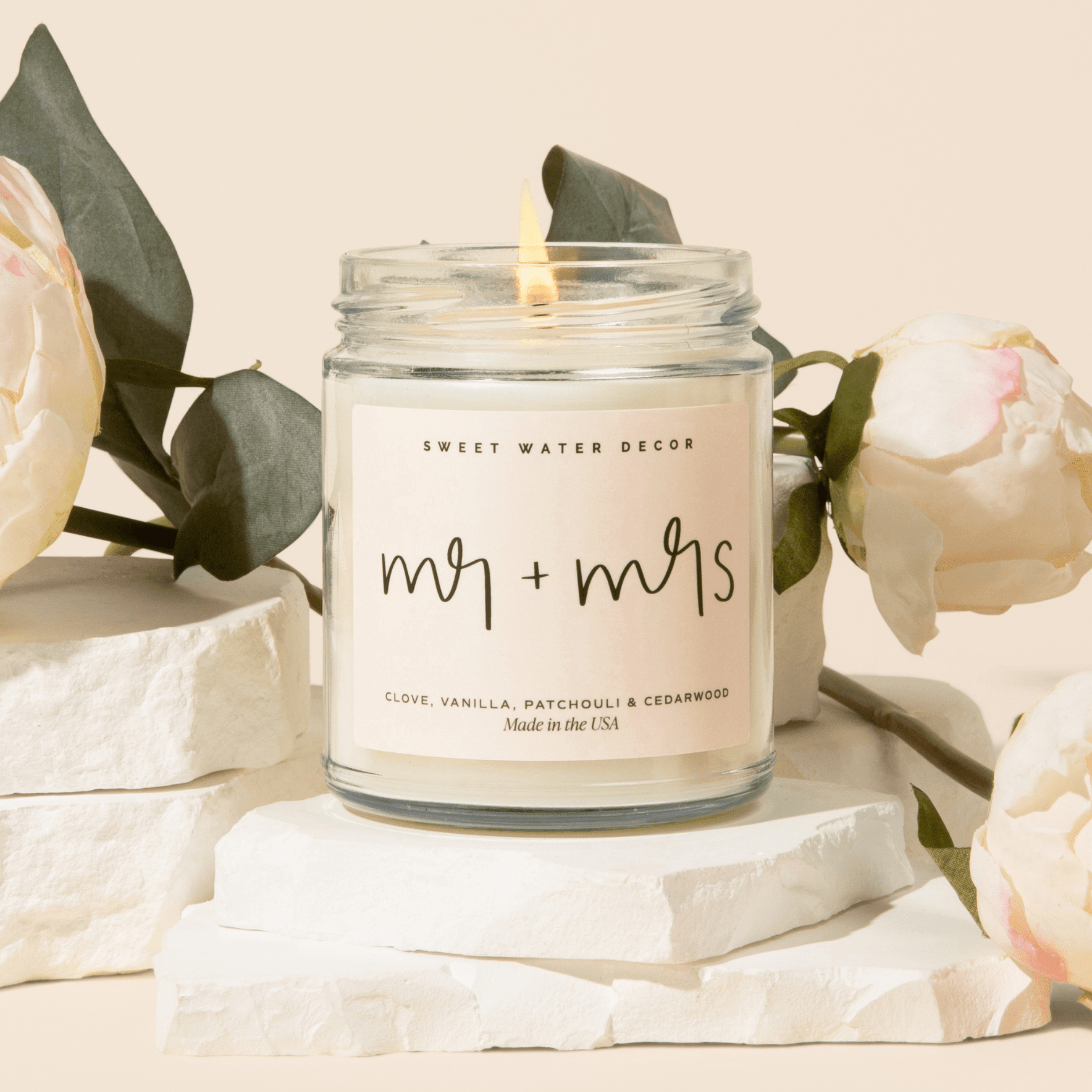 Clear glass jar candle with "mr + mrs" text and floral arrangements on neutral background