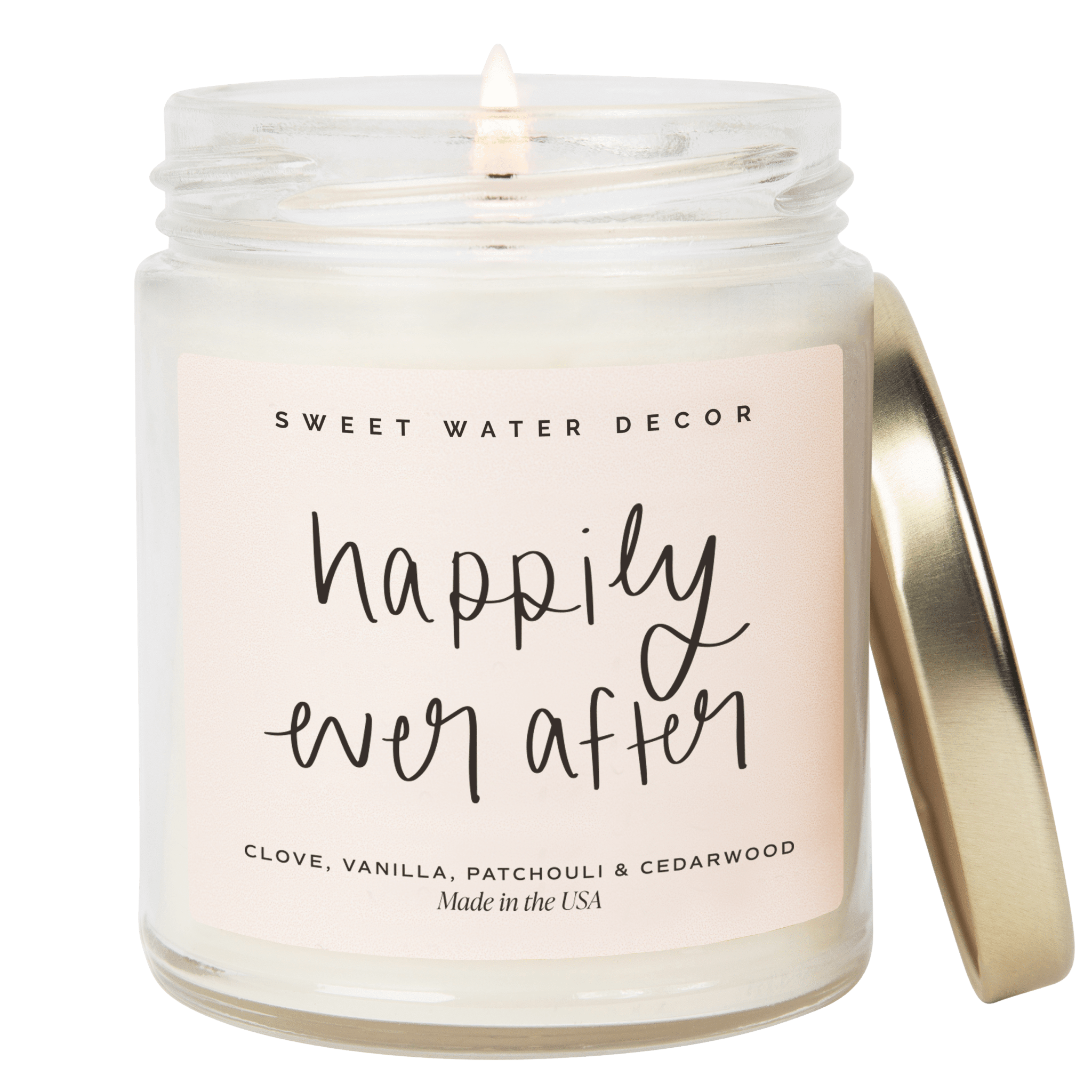 Clear glass jar candle with gold lid and "happily ever after" handwritten text, scented with clove, vanilla, patchouli and cedarwood.