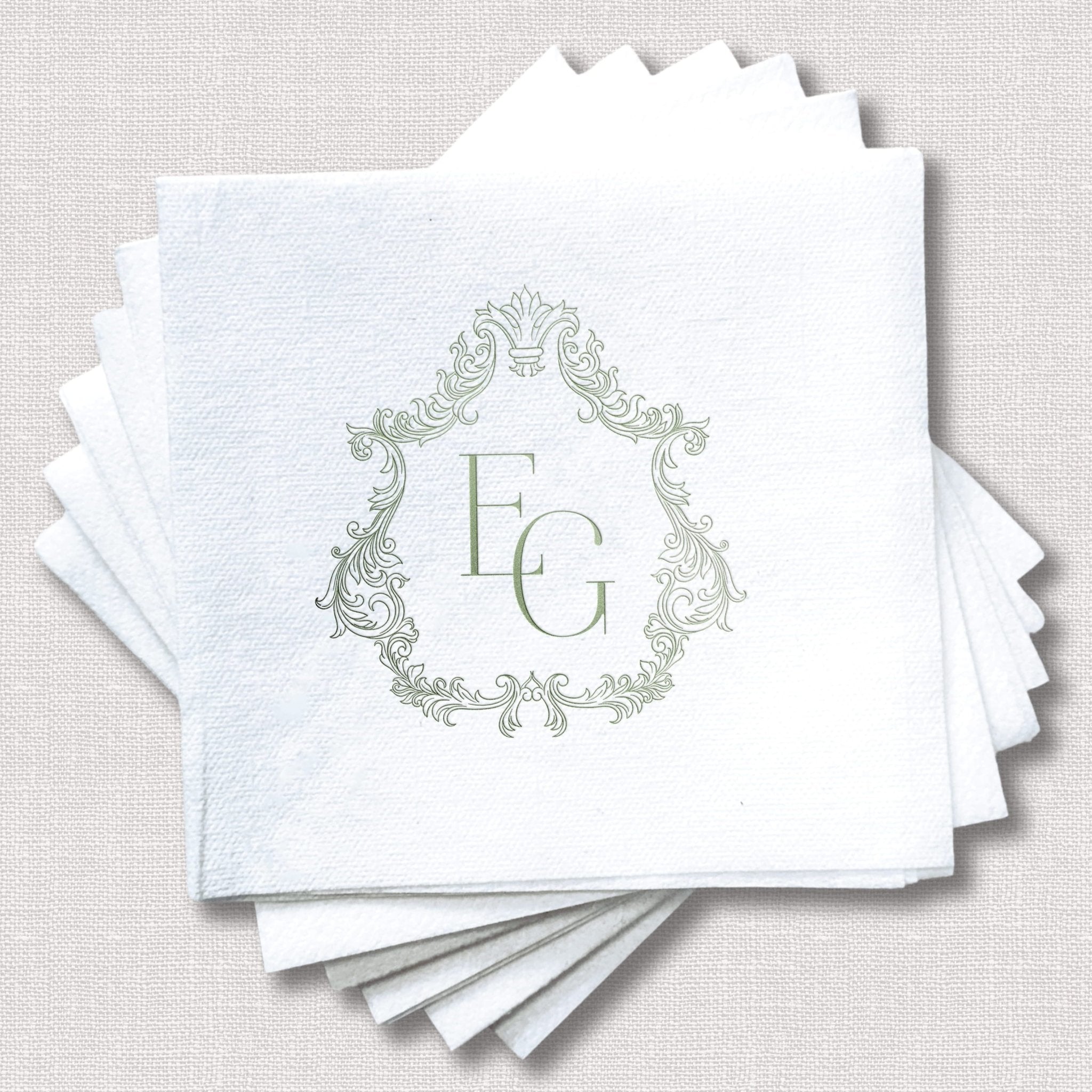 Stack of white napkins with ornate frame monogram design and initials FG in silver foil stamping