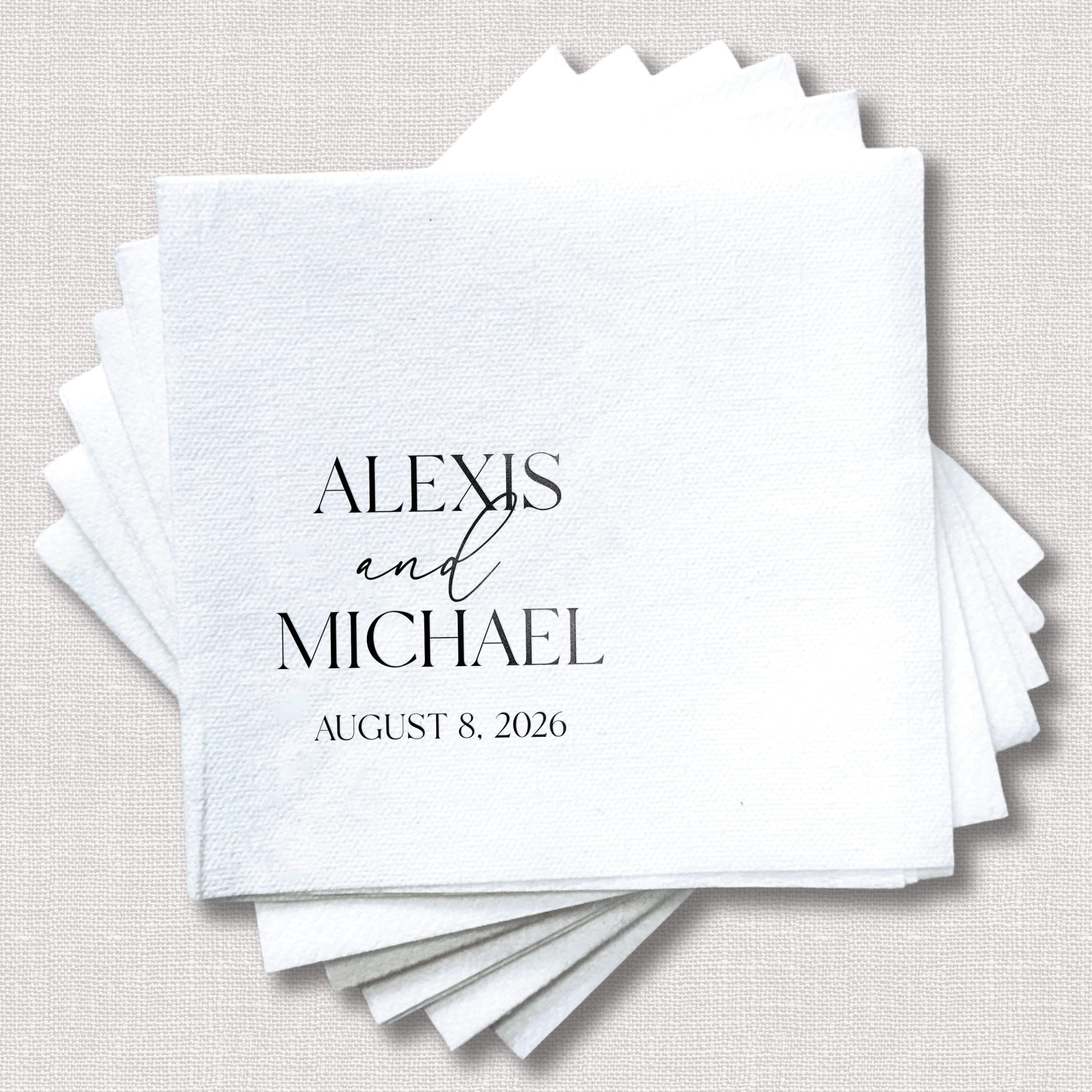 Stack of white linen napkins personalized with Alexis and Michael wedding date August 8, 2026