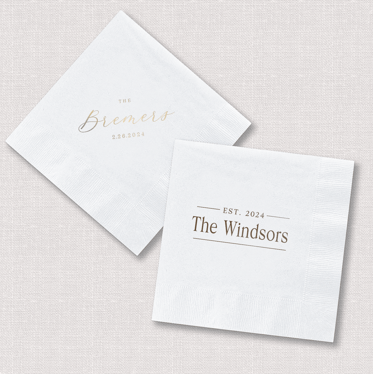 White foil stamped napkins with personalized text, one showing "Emerald" and the other displaying "EST. 2024 The Windsors" in elegant lettering.