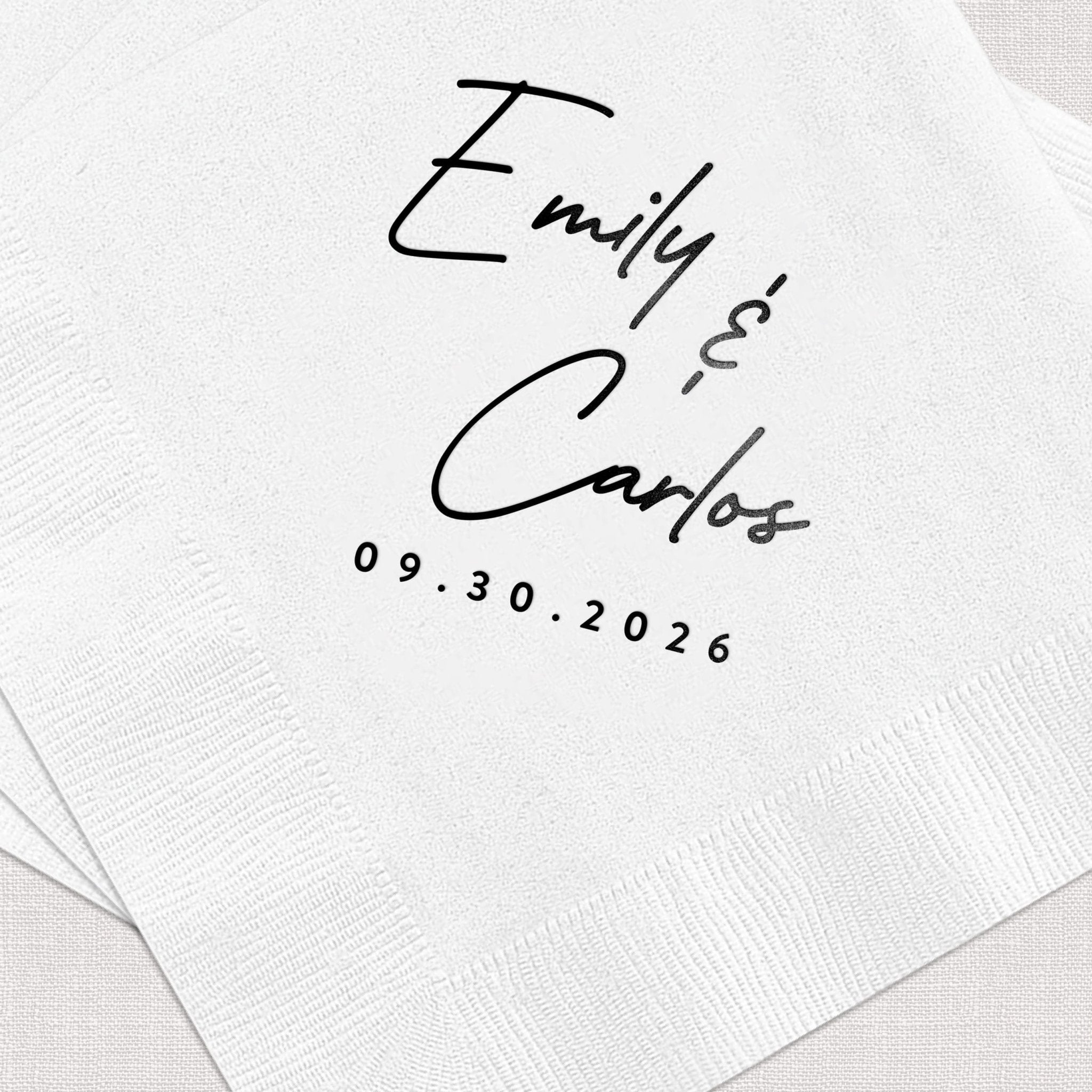White napkin with handwritten script names "Emily & Carlos" and wedding date 09.30.2026 in black ink.