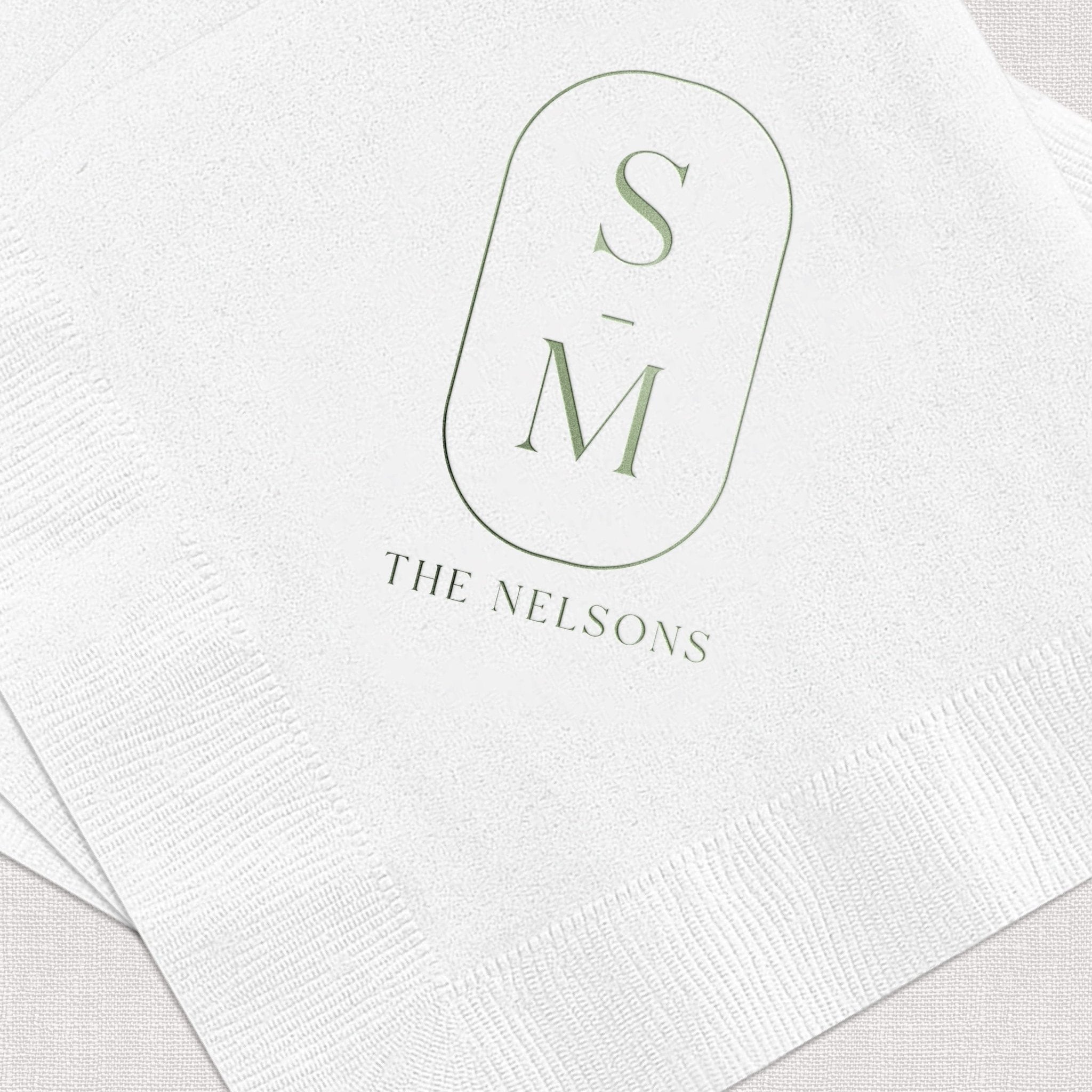 White napkins with sage green monogram S and M inside rounded rectangle, text reading "THE NELSONS" below