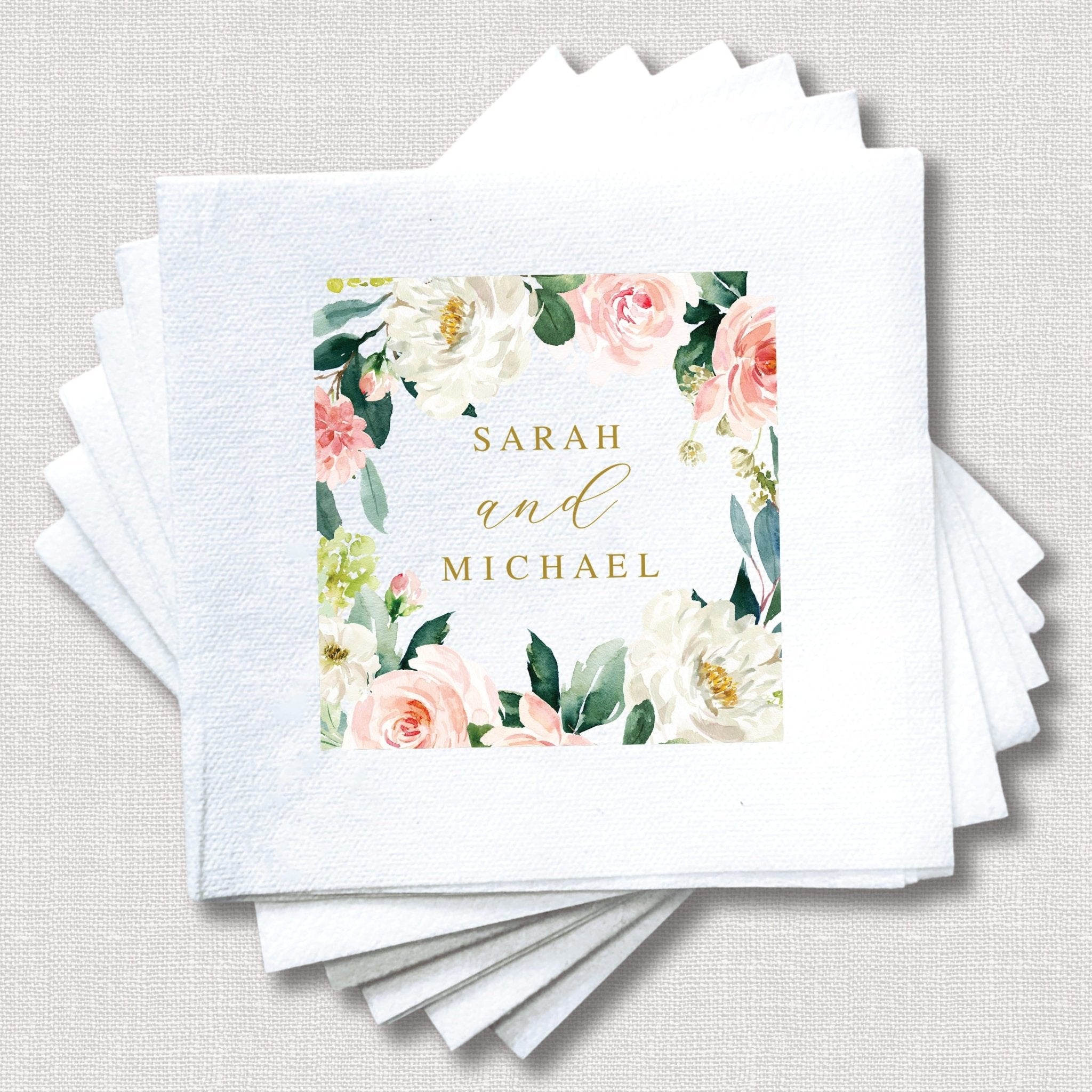 White napkins with watercolor floral border and gold text reading "SARAH and MICHAEL"