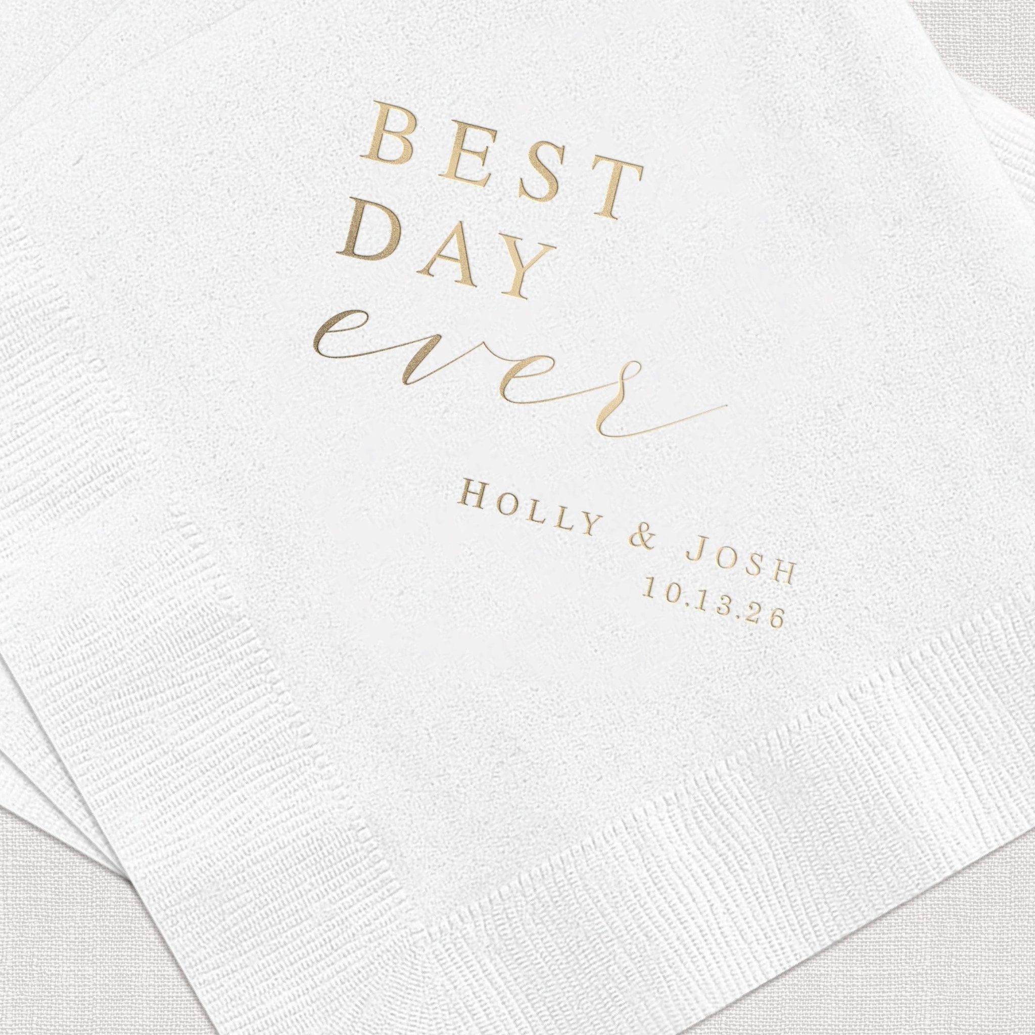White napkins with gold foil stamped text reading "BEST DAY ever" and personalized names "HOLLY & JOSH" with date "10.13.25"