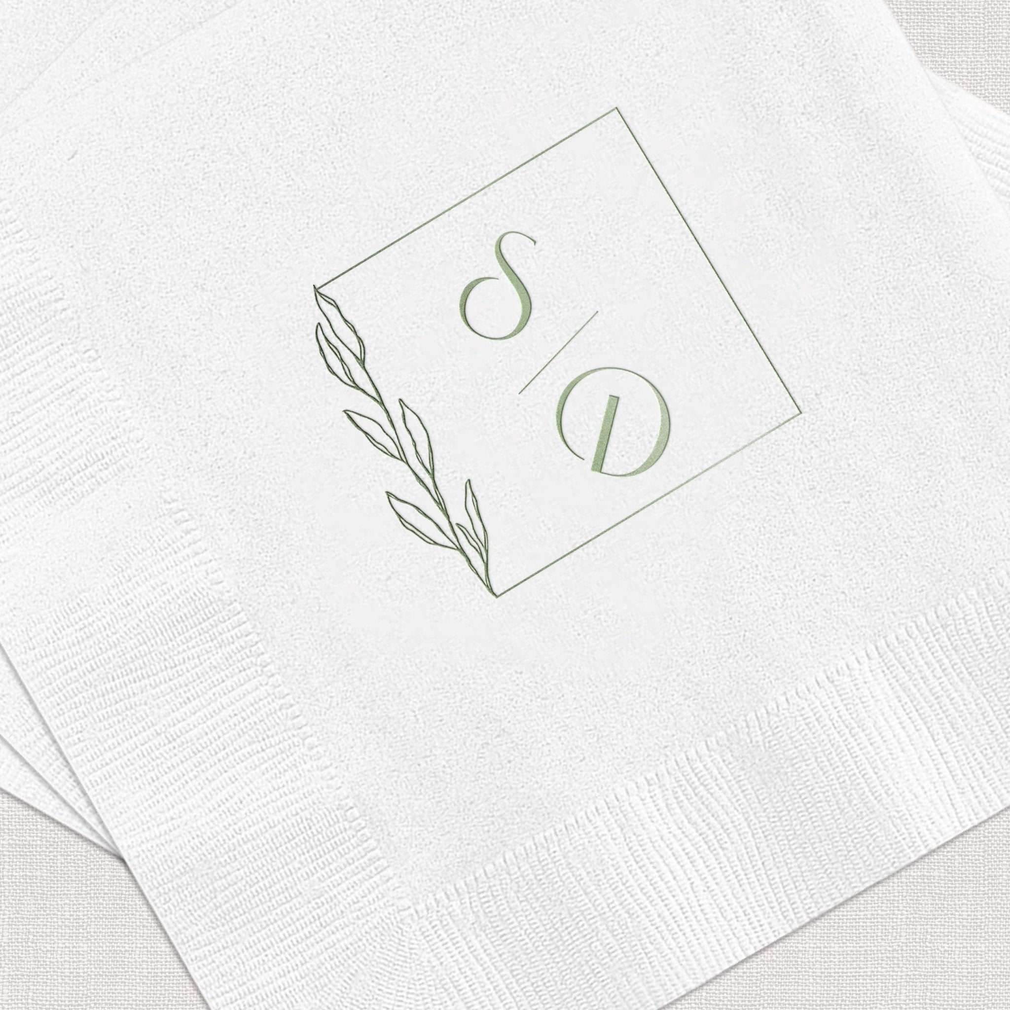 White napkin with sage green foil-stamped monogram S and D with leaf design detail.