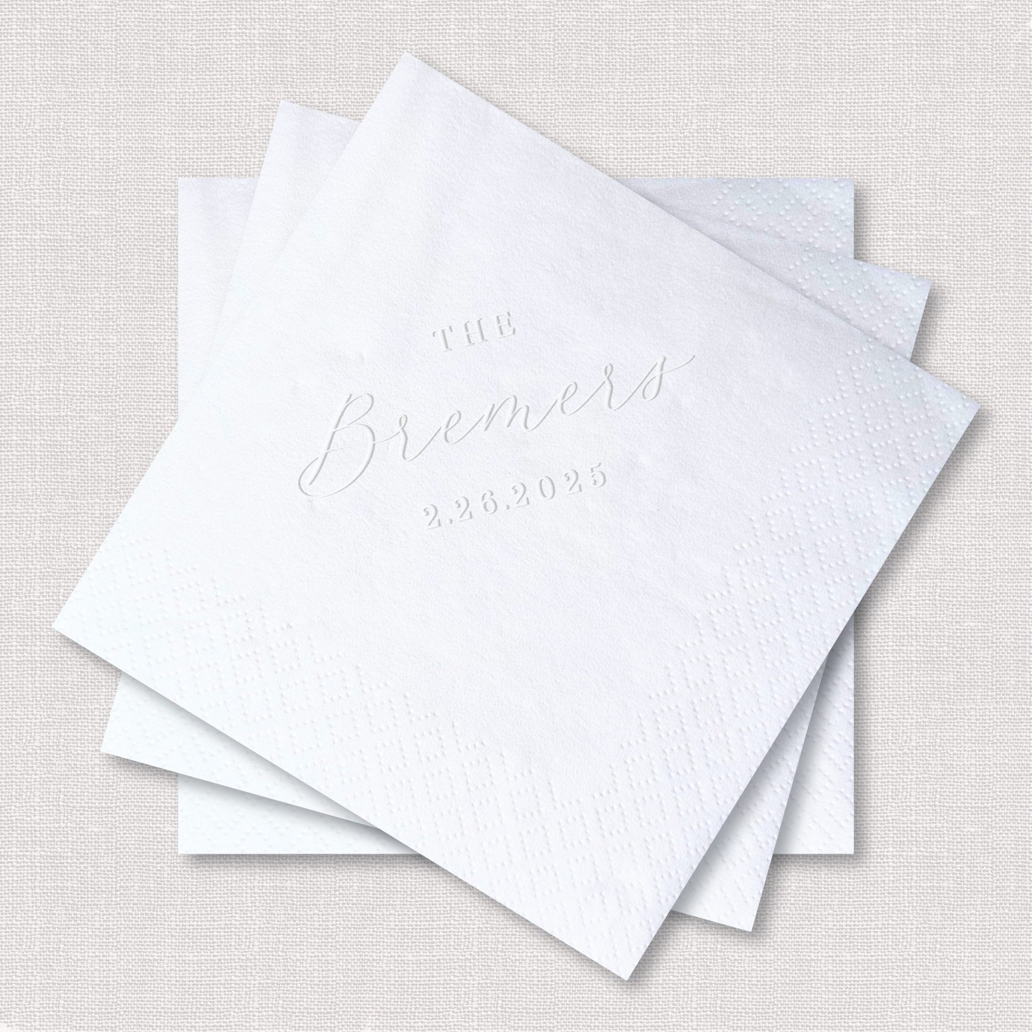 Stack of white embossed napkins with "The Brandt" and date "2.24.2024" personalized in elegant script lettering