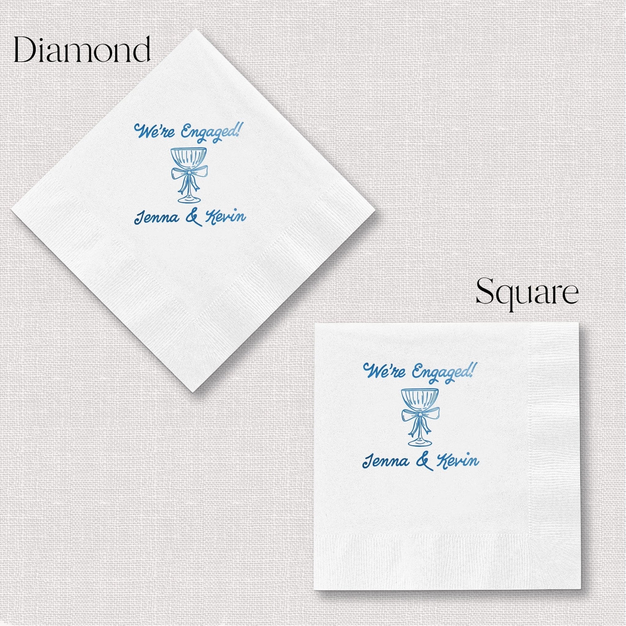White cocktail napkins with blue foil-stamped "We're Engaged" text, champagne glass design, and personalized names in diamond and square shapes.
