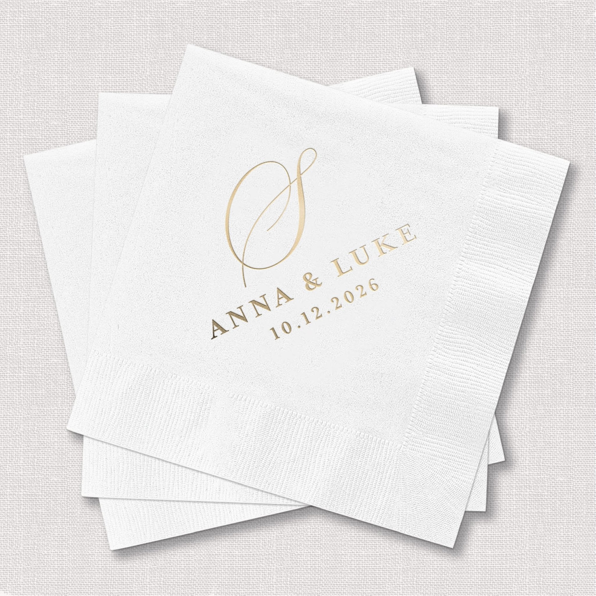 Stack of white napkins with gold foil monogram and names Anna and Luke with date 10.12.2028