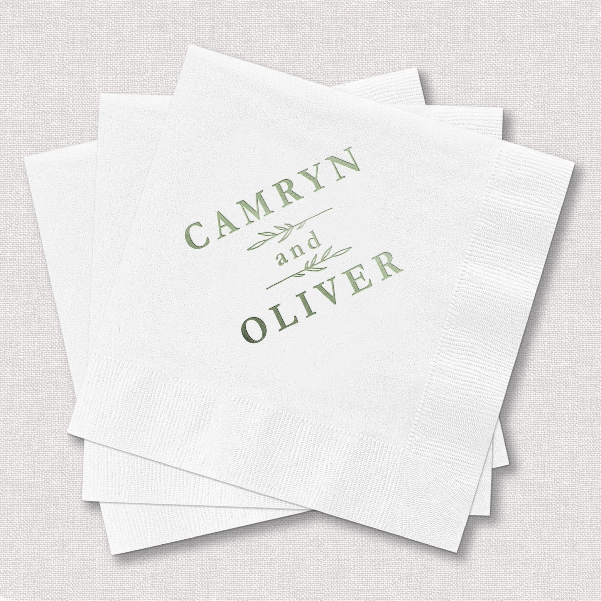 White foil-stamped napkins with "Camryn and Oliver" in sage green text and decorative botanical line