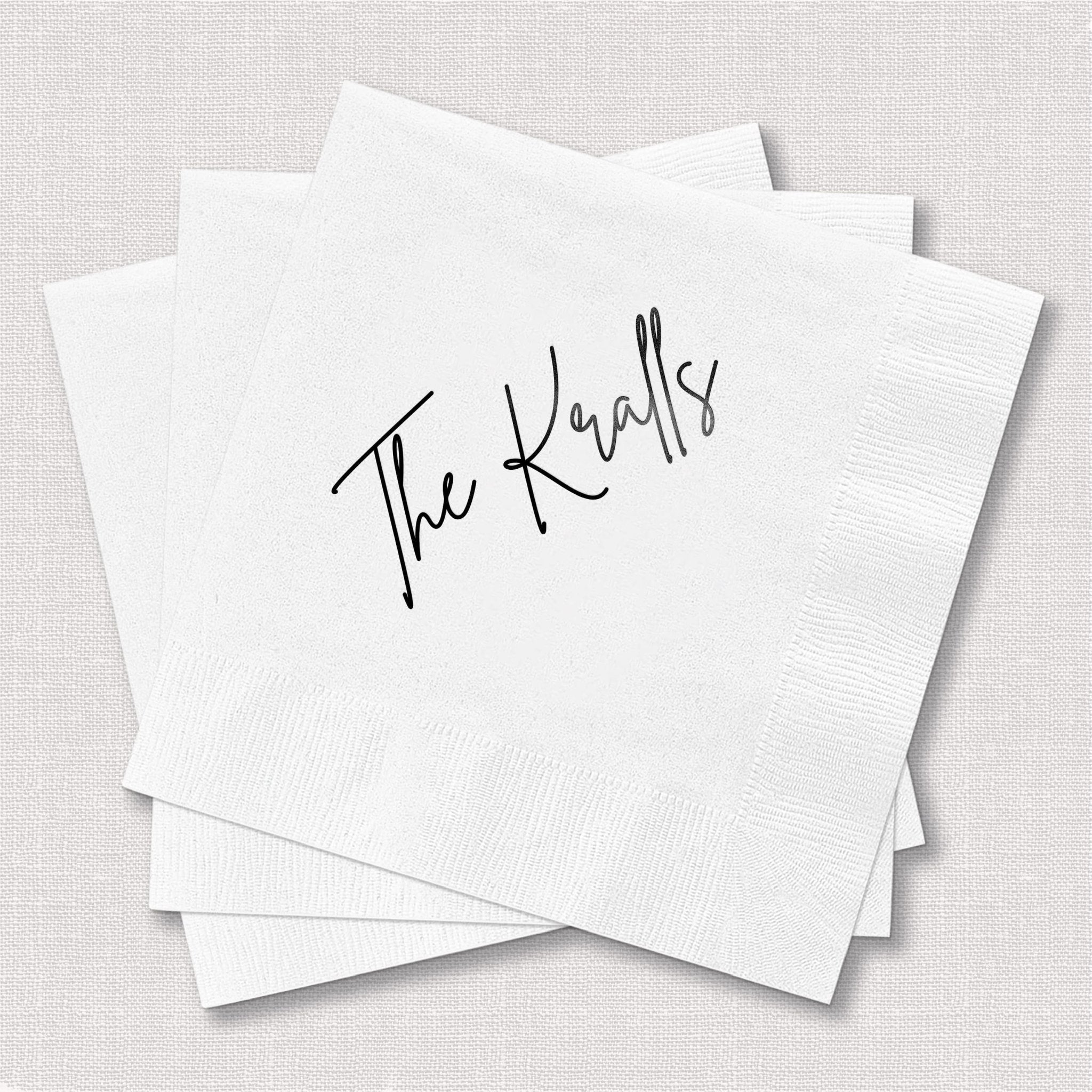 White cocktail napkins with "The Kendalls" in black script lettering, stacked and fanned out