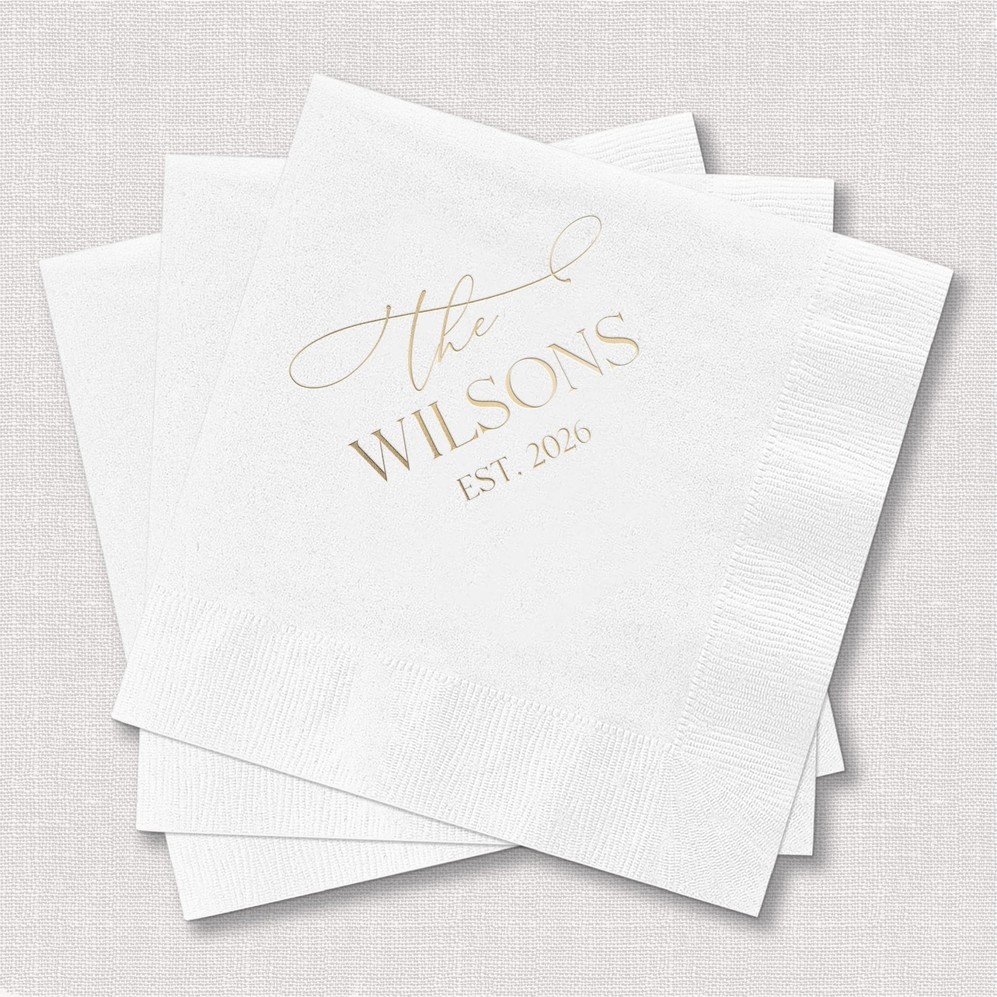 White cocktail napkins with gold foil stamped "The Wilsons EST 2020" personalization text