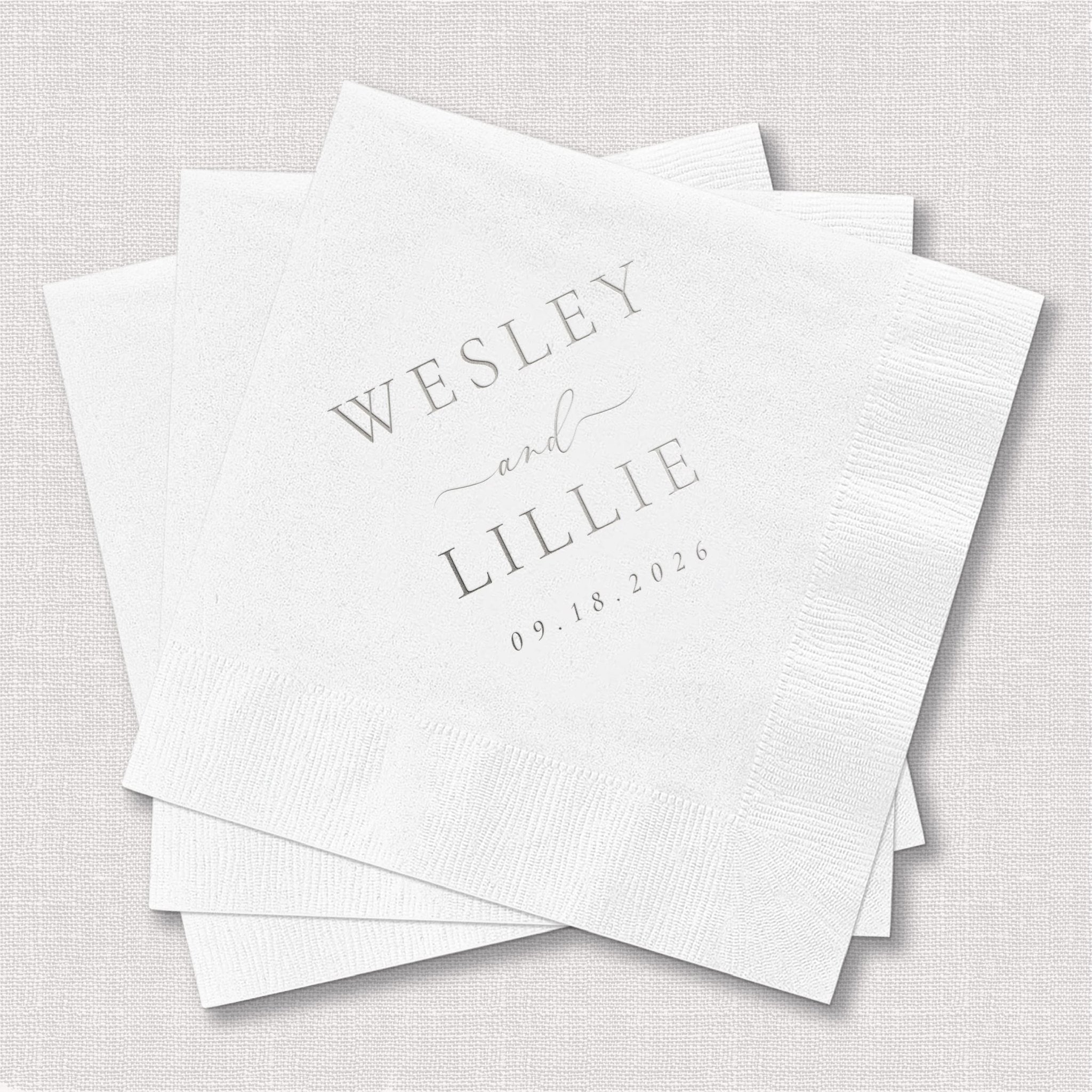 White foil-stamped napkins with "Wesley and Lillie" and wedding date "09.18.2026" printed in silver text.