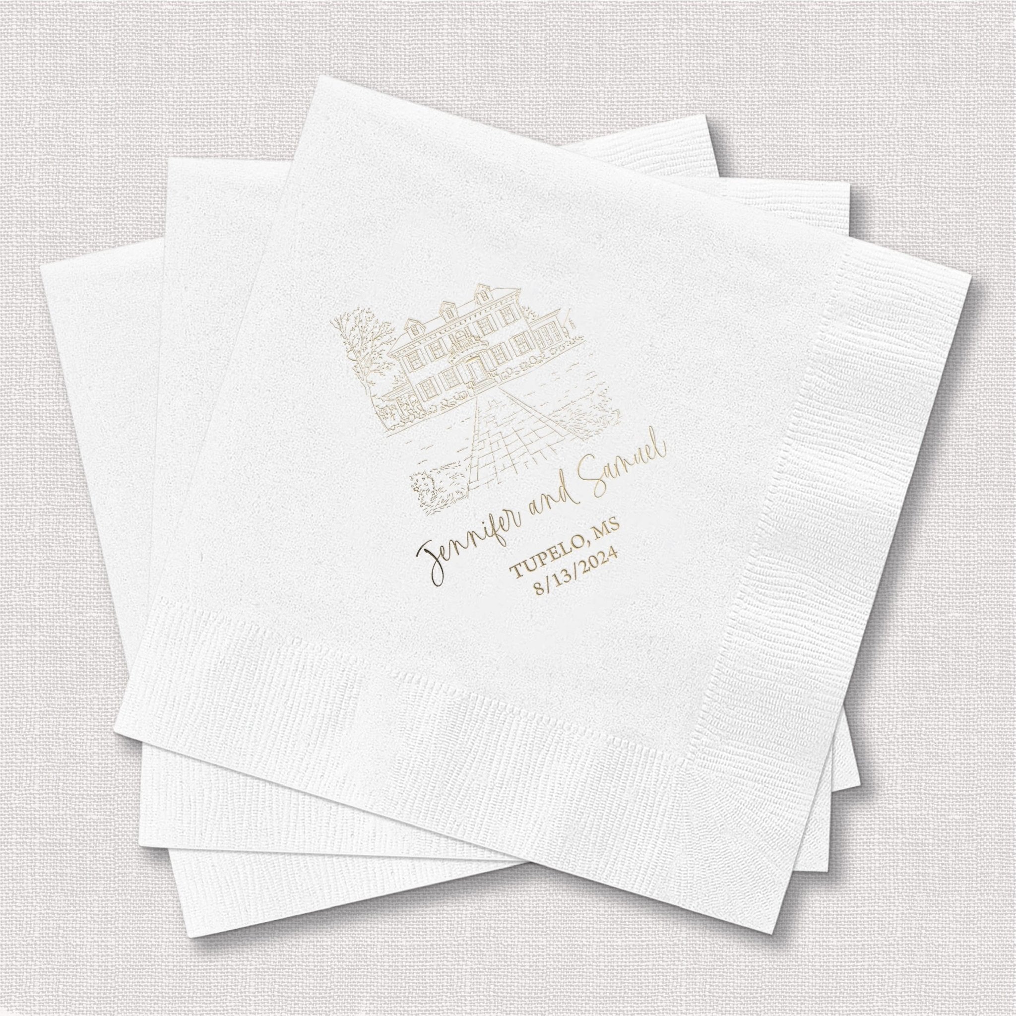 Stack of white napkins with gold venue illustration and personalized names and wedding date printed in script.