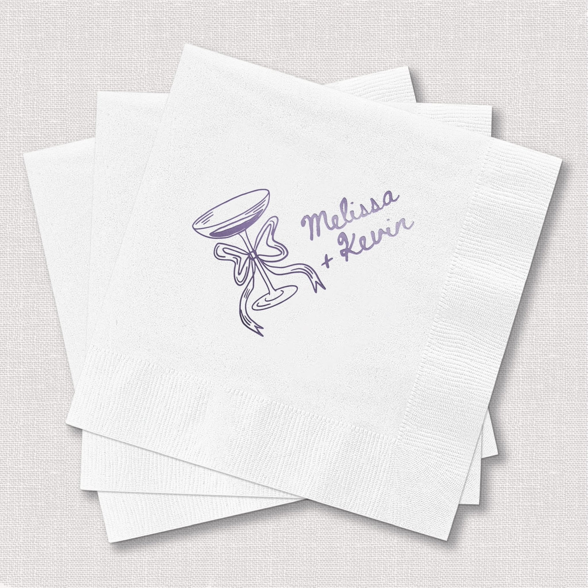 White foil-stamped napkins with champagne glass doodle and "Melissa + Levi" personalization in purple ink