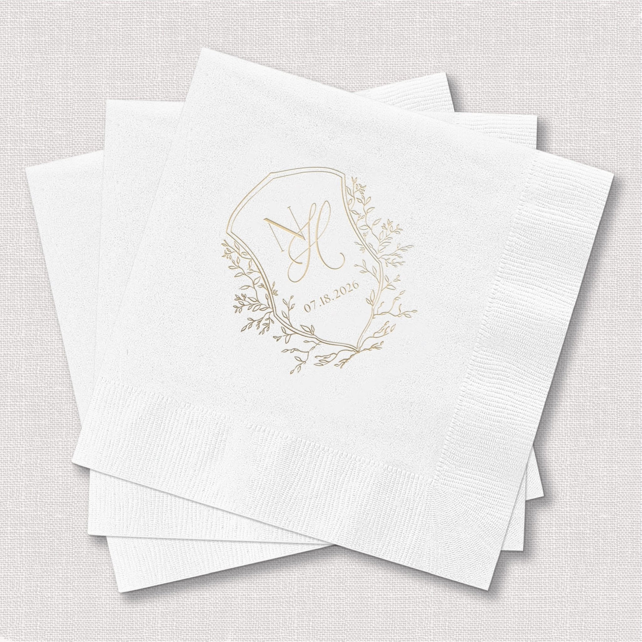 Stack of white napkins with gold foil botanical wreath and monogram design