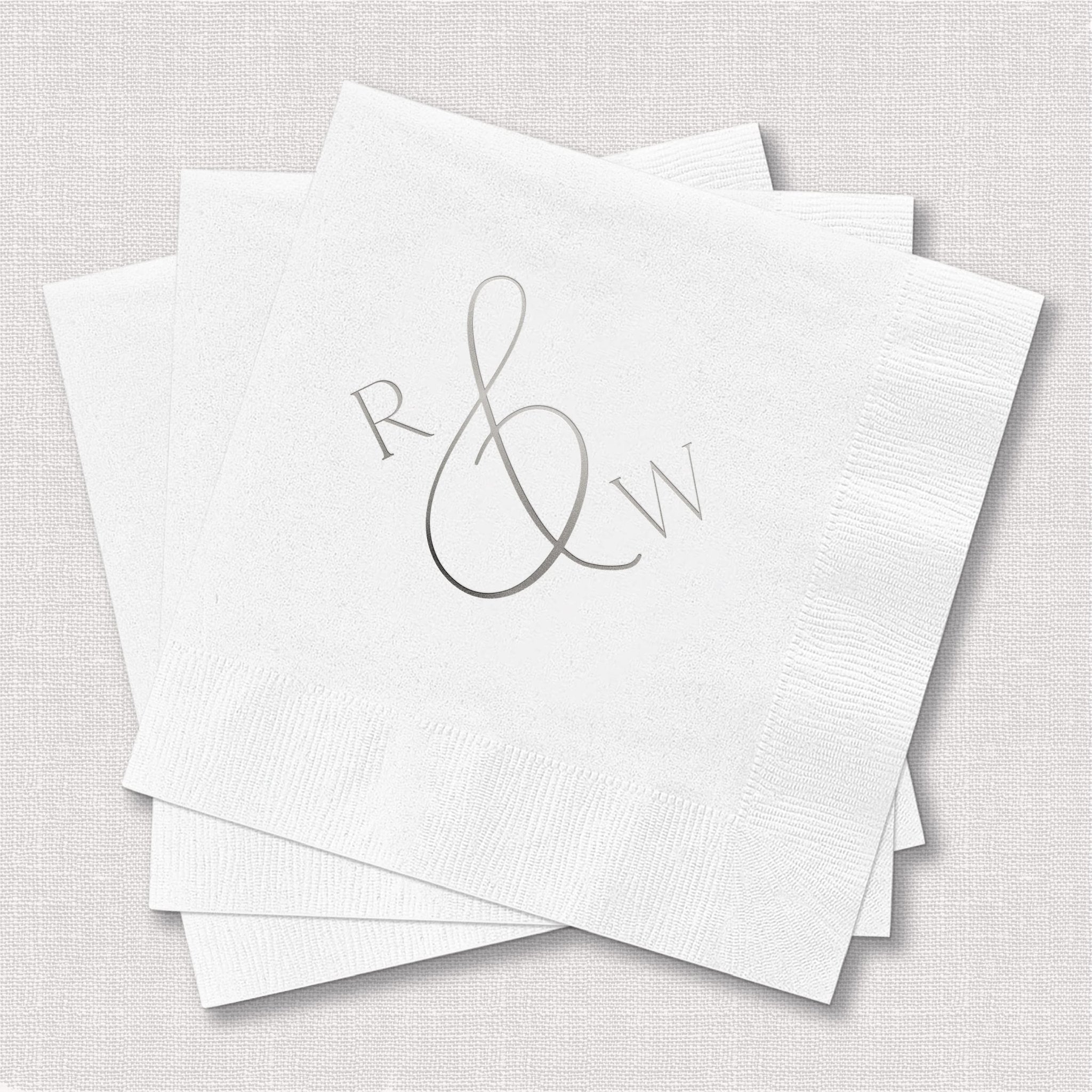 White cocktail napkins with silver foil stamped monogram featuring initials R and W with decorative ampersand design