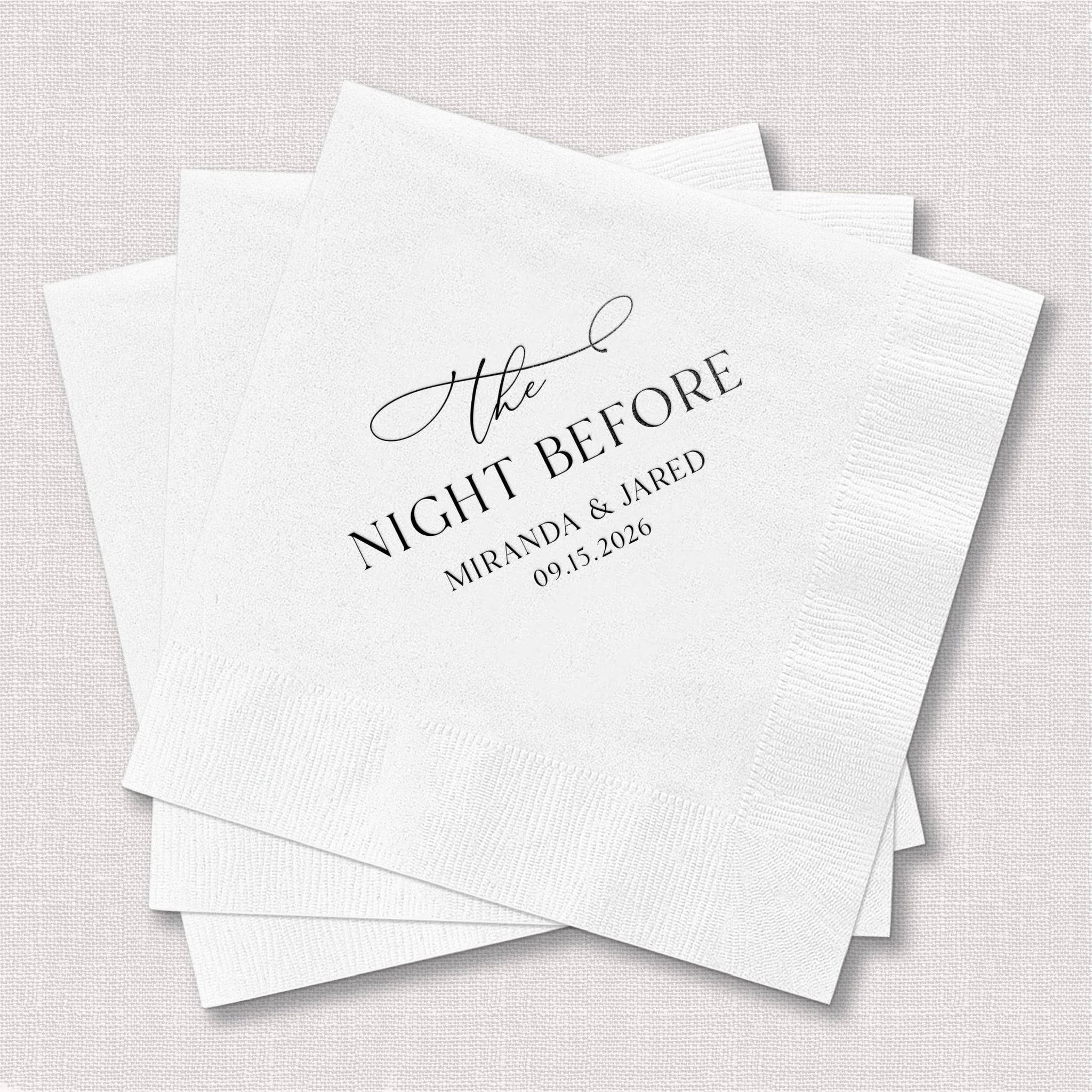 Stack of white cocktail napkins with "The Night Before" in script and "MIRANDA & JARED 07.13.2026" in elegant gray foil stamping.