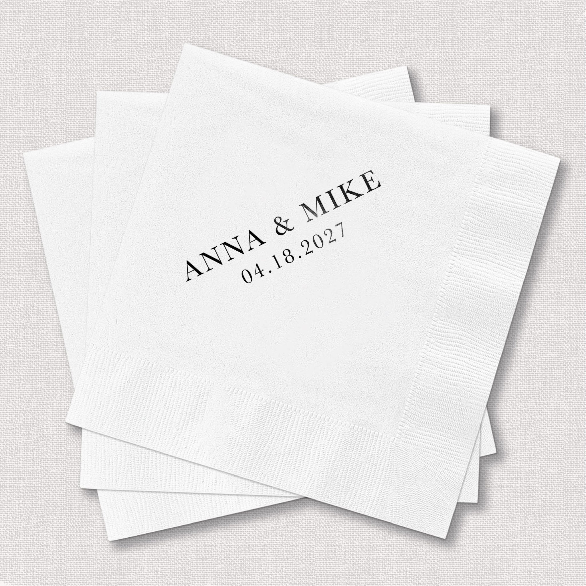 Stack of white cocktail napkins with "ANNA & MIKE 04.18.2021" printed in black text