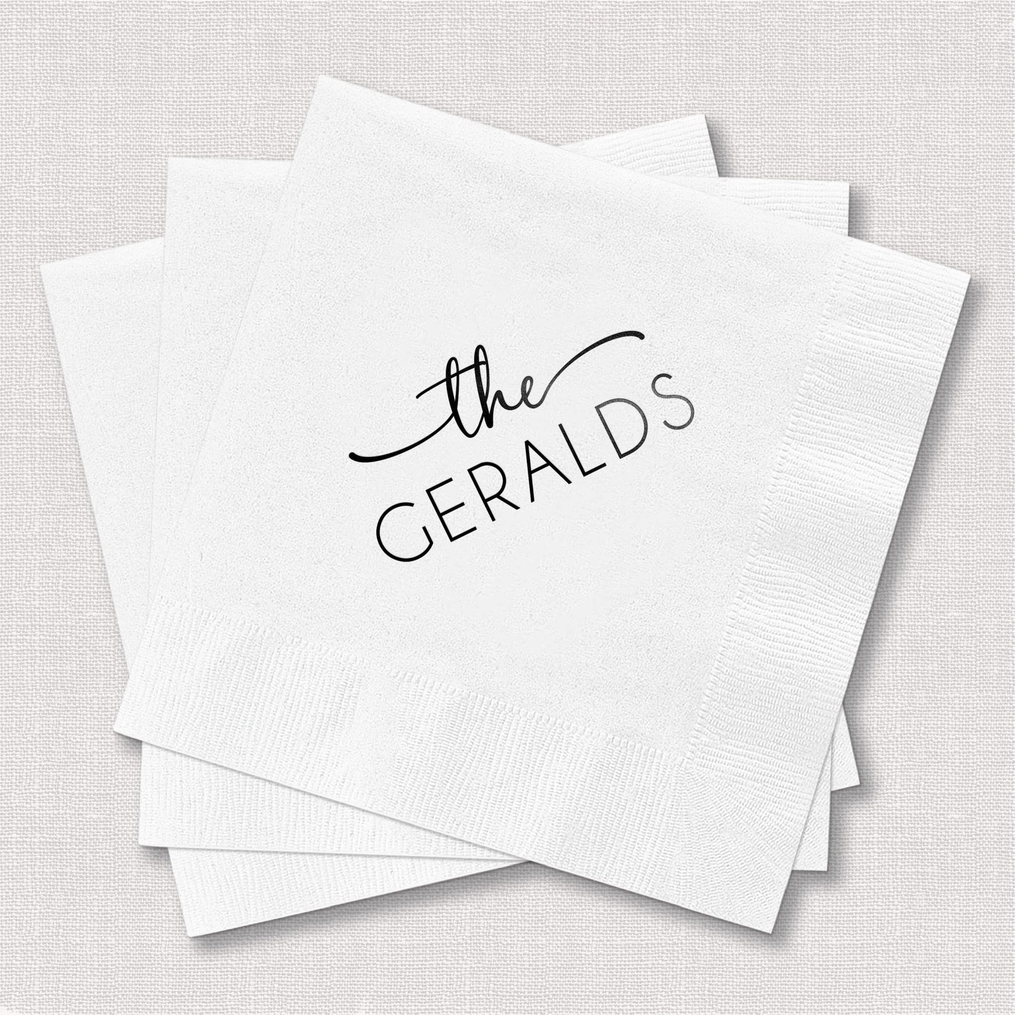 Stack of white napkins personalized with "the GERALDS" in black foil stamped text