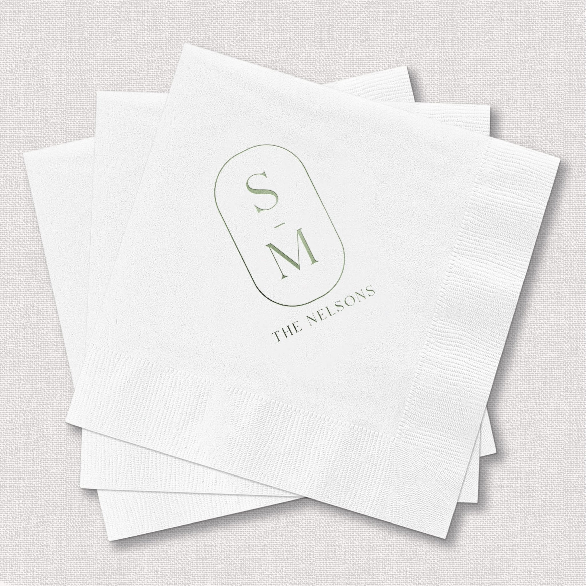 Stack of white personalized napkins with monogram S M and "The Seasons" text in foil stamping design.
