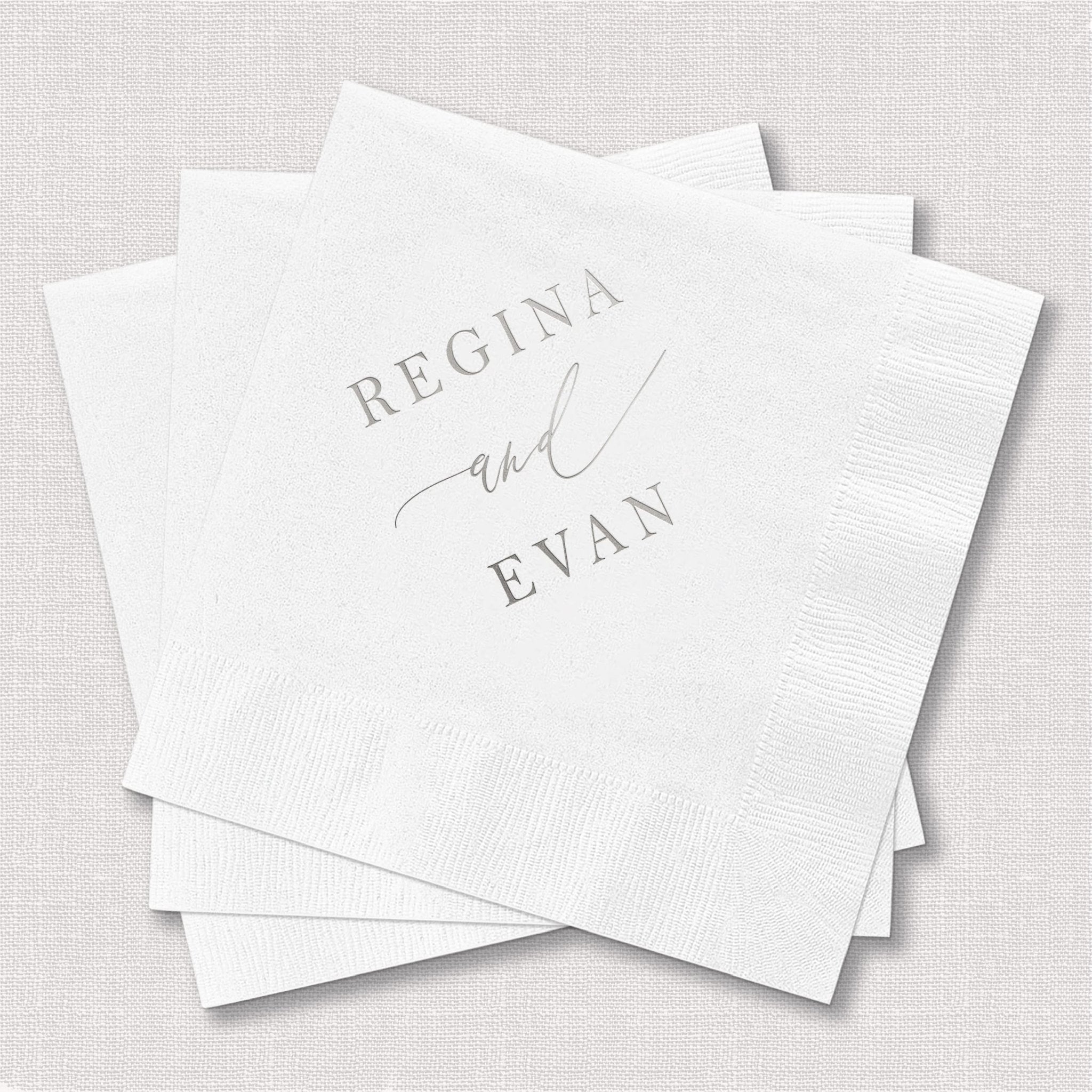 White cocktail napkins with "Regina and Evan" in gray foil lettering