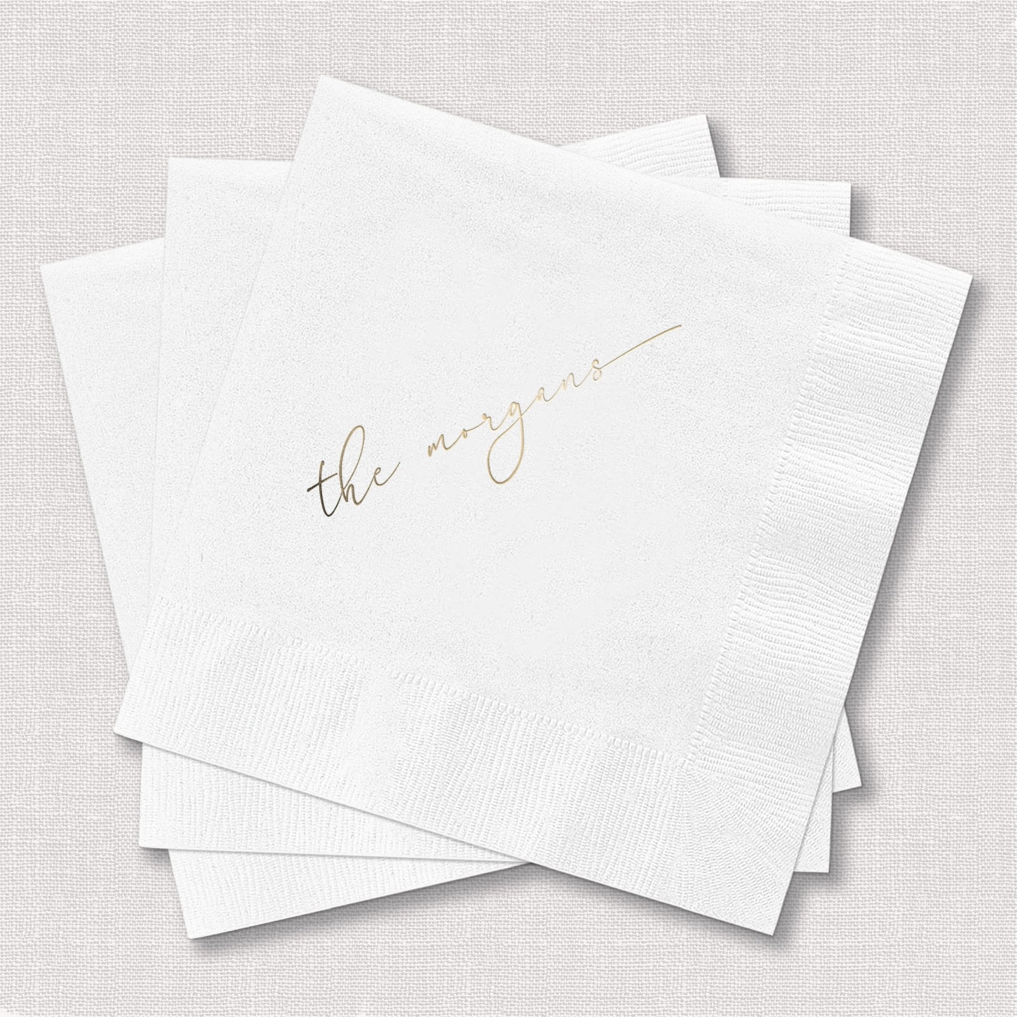 White foil-stamped cocktail napkins with "the maggies" in gold script text