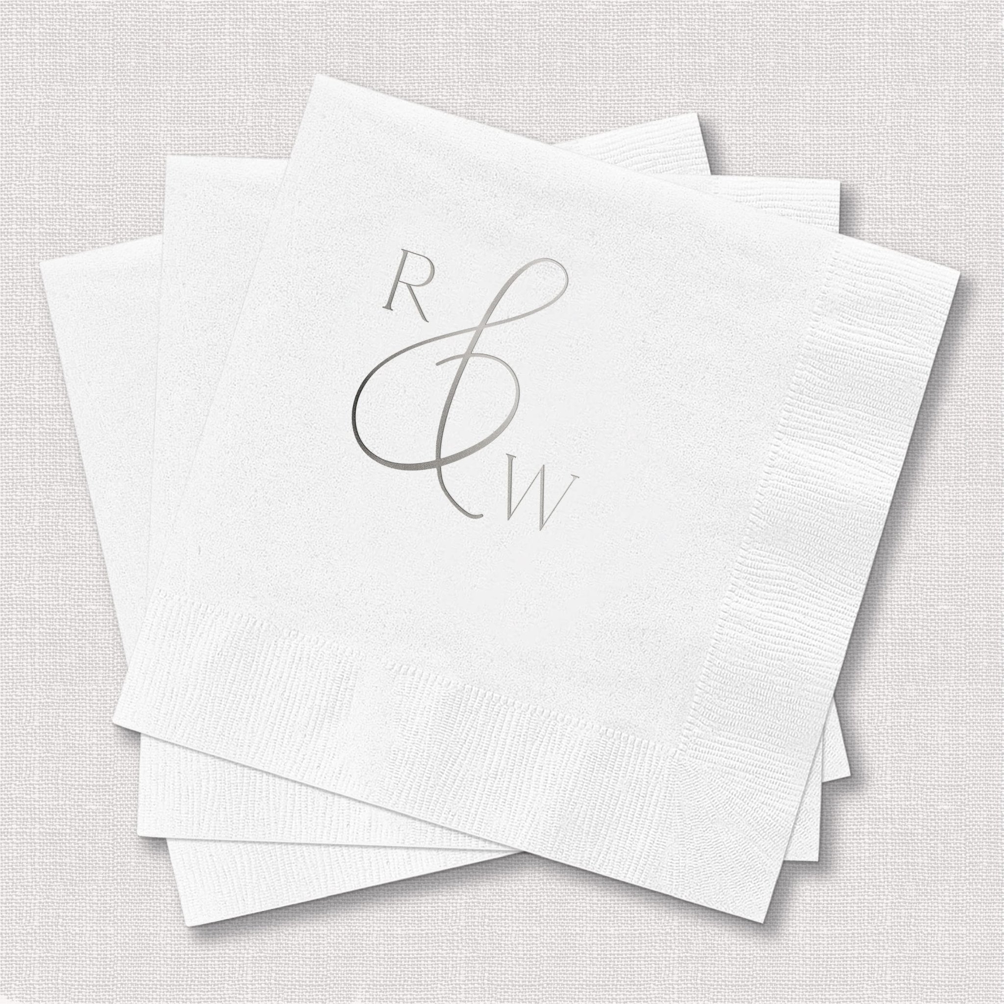 Stack of white napkins with silver foil stamped monogram featuring R and W initials intertwined in elegant script design