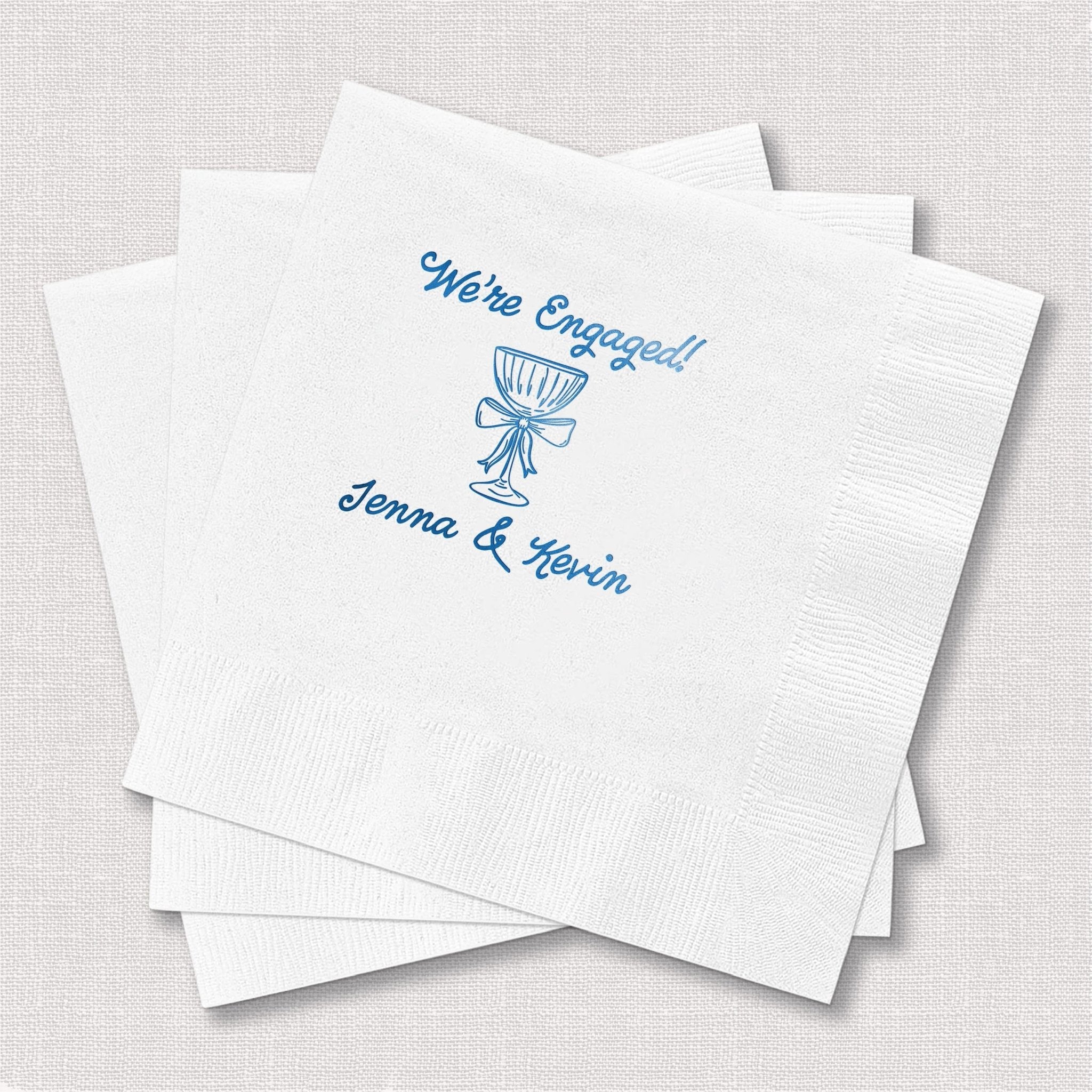 White cocktail napkins with blue foil-stamped engagement design and personalized names Jenna and Kevin