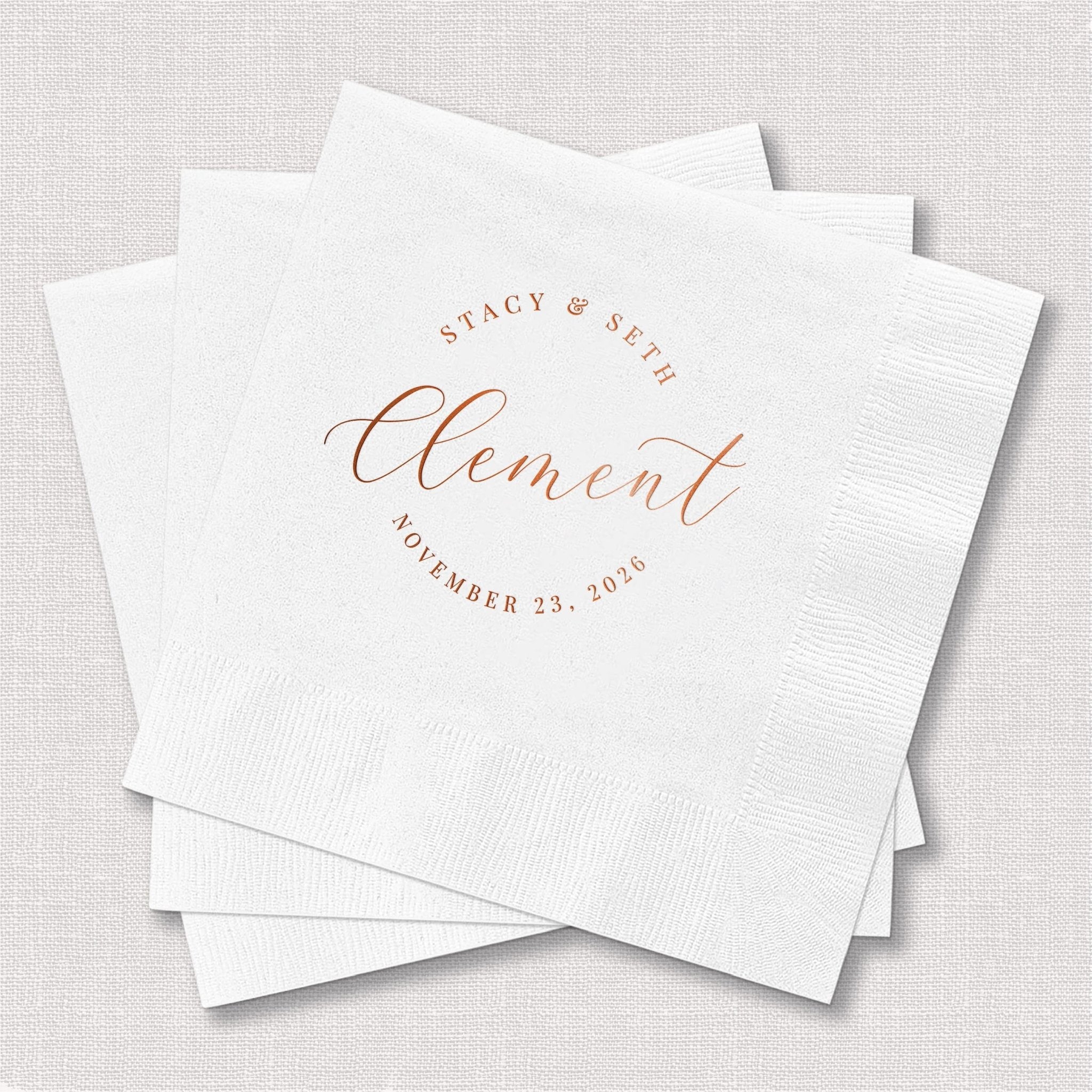 White cocktail napkins with rose gold foil stamped text reading "Stacy & Seth" and "Clement" with date "November 23, 2024"