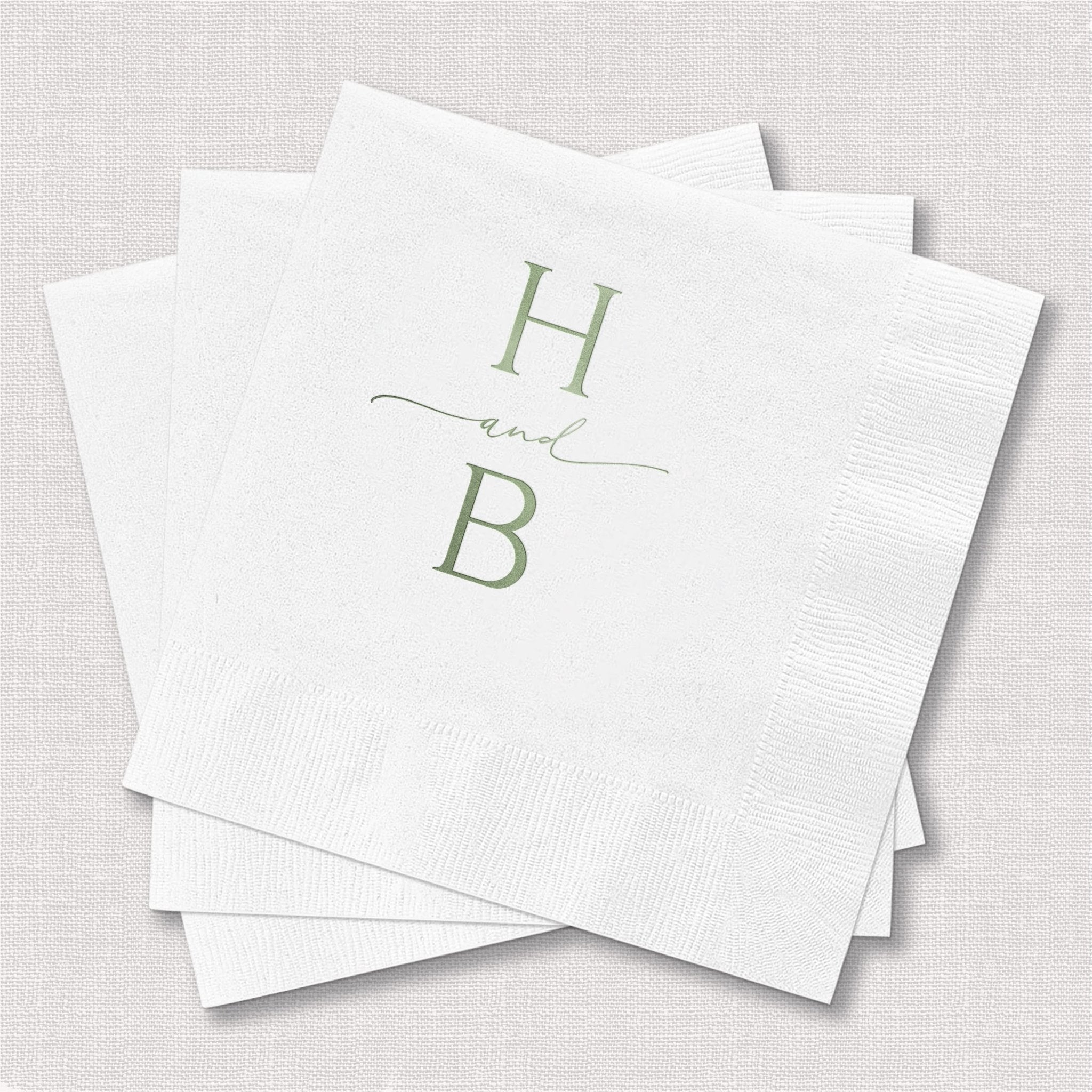 Stack of white napkins with sage green foil-stamped monogram initials H and B with decorative line