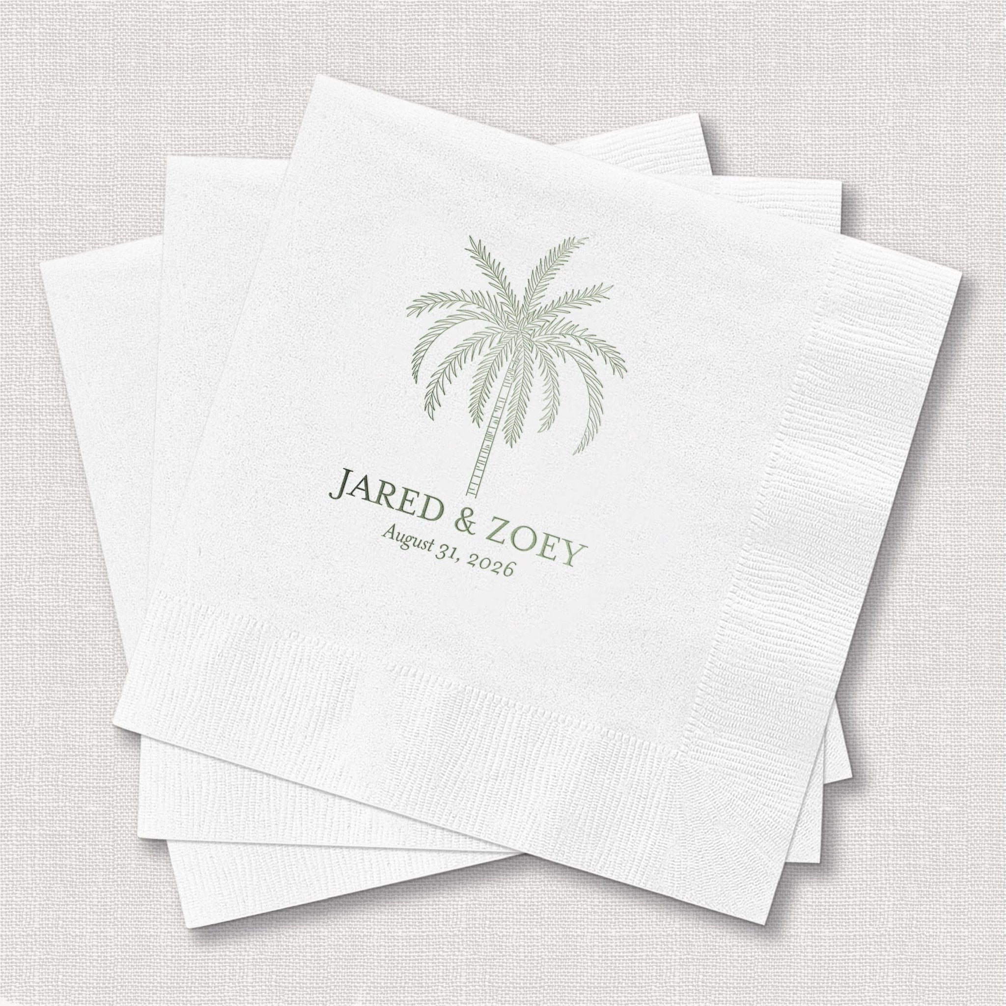 Stack of white cocktail napkins with palm tree design and "Jared & Zoey" personalization in foil stamping