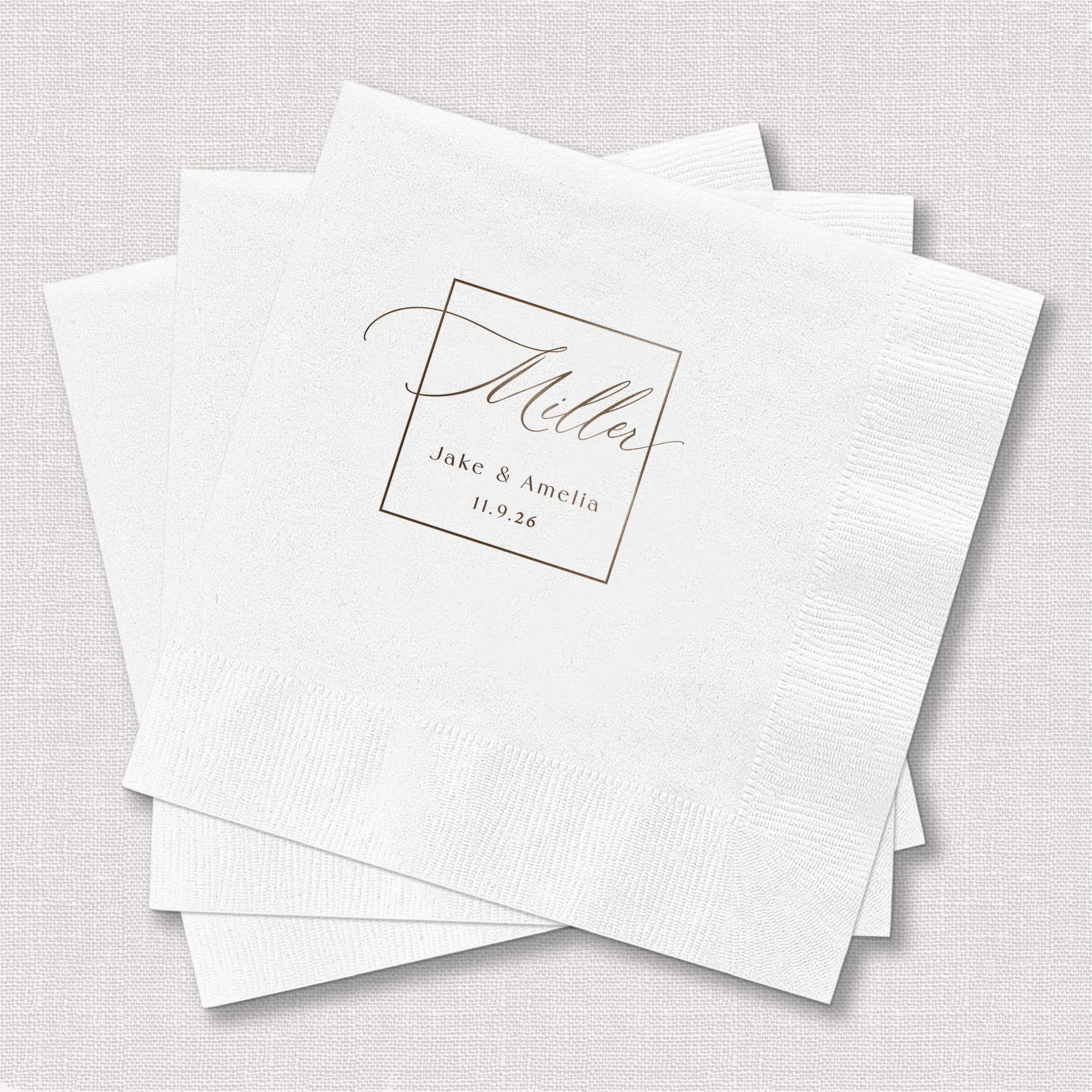 White foil-stamped napkins with elegant monogram design featuring names and wedding date in gray script lettering.