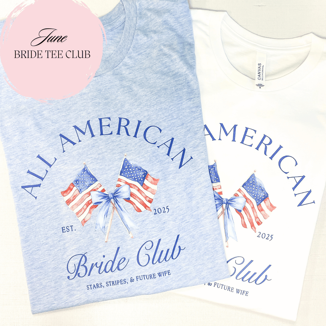 All American Bride Club t-shirts in light blue and cream with flag design and personalized names, displayed flat lay with pink logo circle.