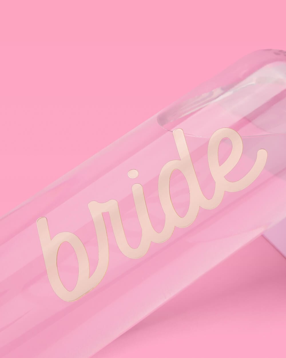 Pink water bottle with cream-colored "bride" text on clear front panel against pink background