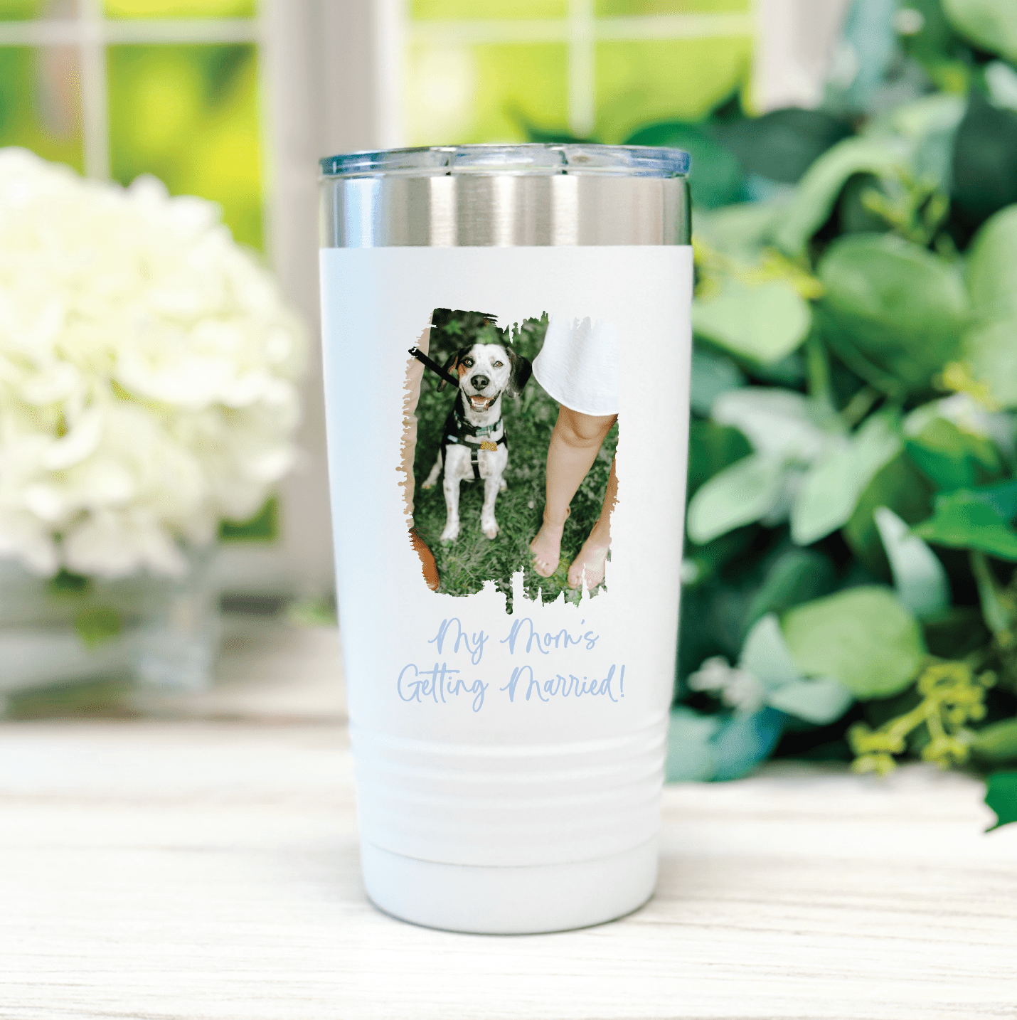 White insulated tumbler with custom dog photo and "My Home Called Pinsrud" text, displayed outdoors near flowers