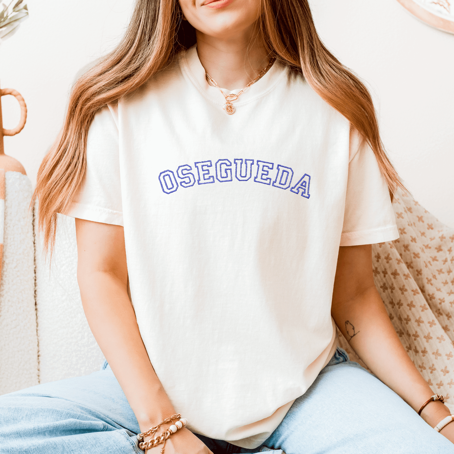 White crewneck t-shirt with blue embroidered "OSEGUEDA" text across the chest