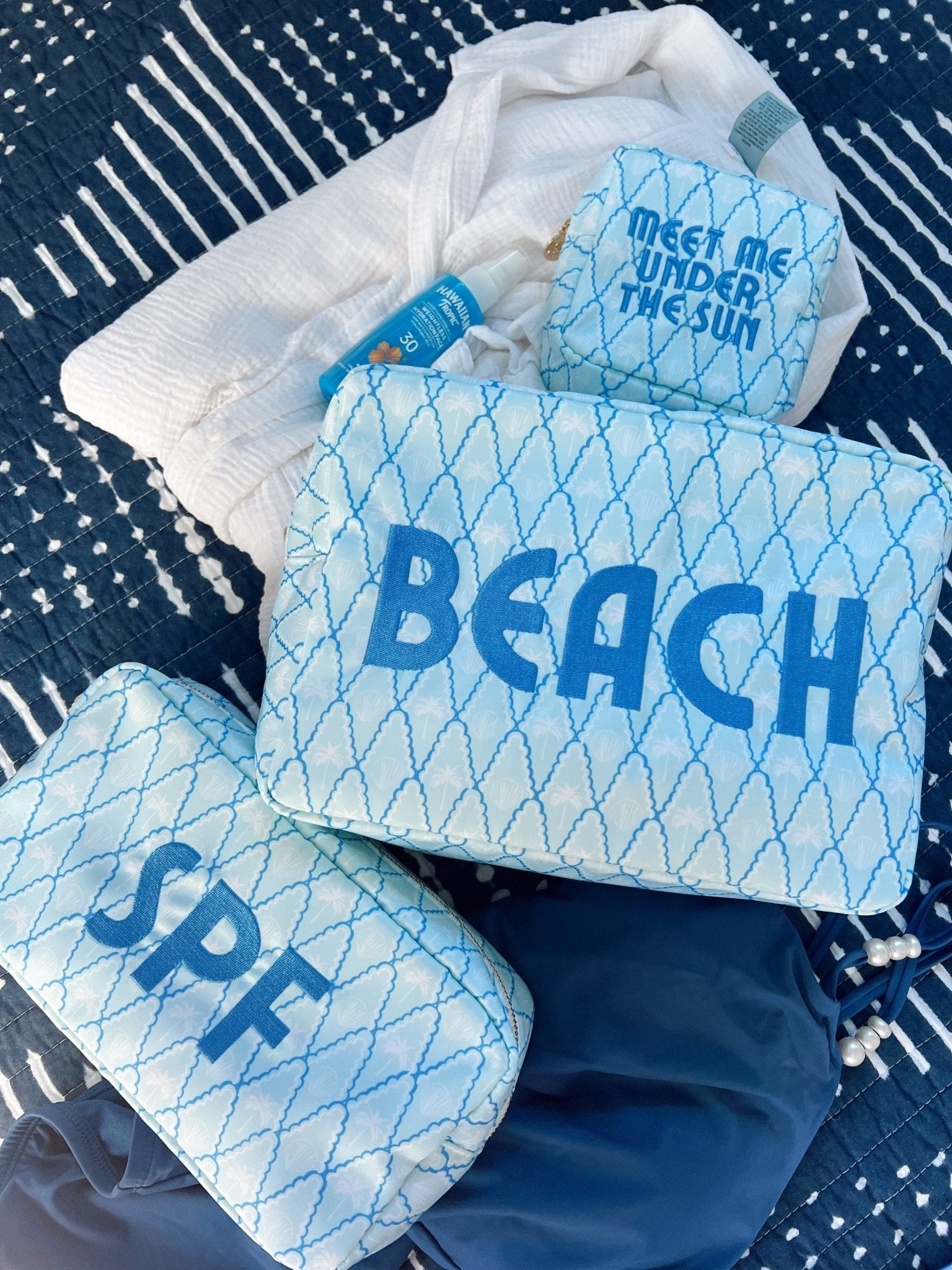 Blue and white mesh makeup bags with "BEACH" and "SPF" text, layered in white tissue paper