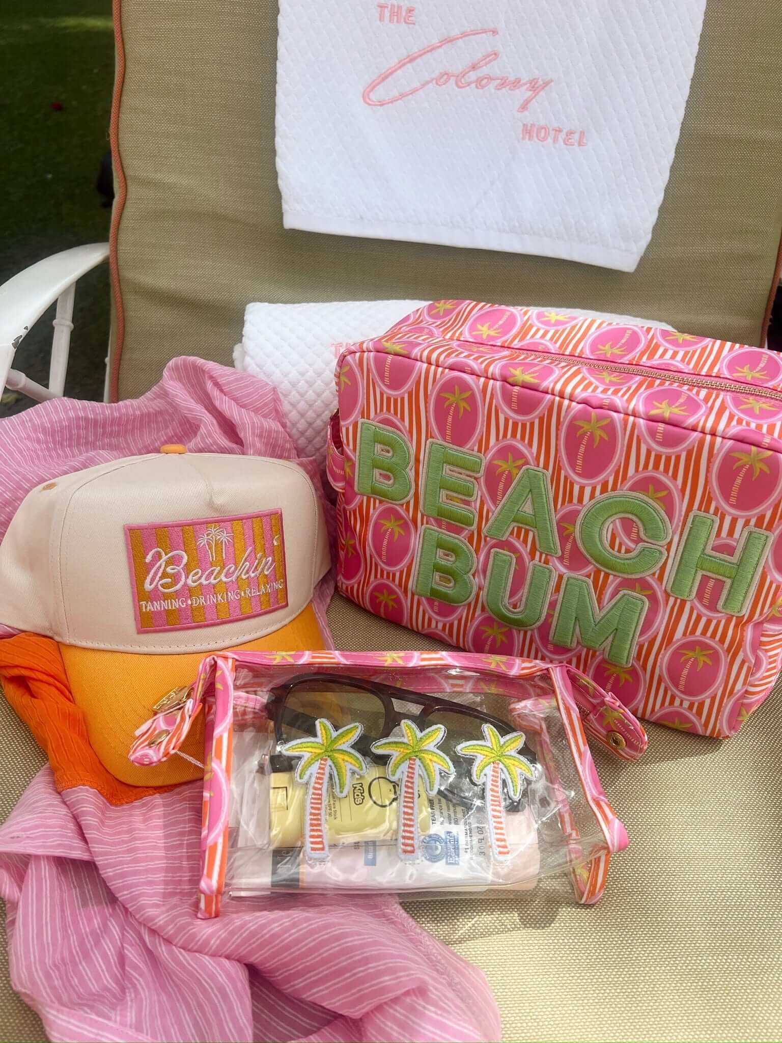 Cream and orange vintage trucker hat with "Beachin'" text and colorful graphic patch, displayed with pink beach-themed party supplies and accessories.